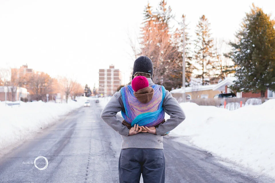 Dad and baby standing in Elmvale Acres walking with baby on dad's back. Baby is in a red hat.