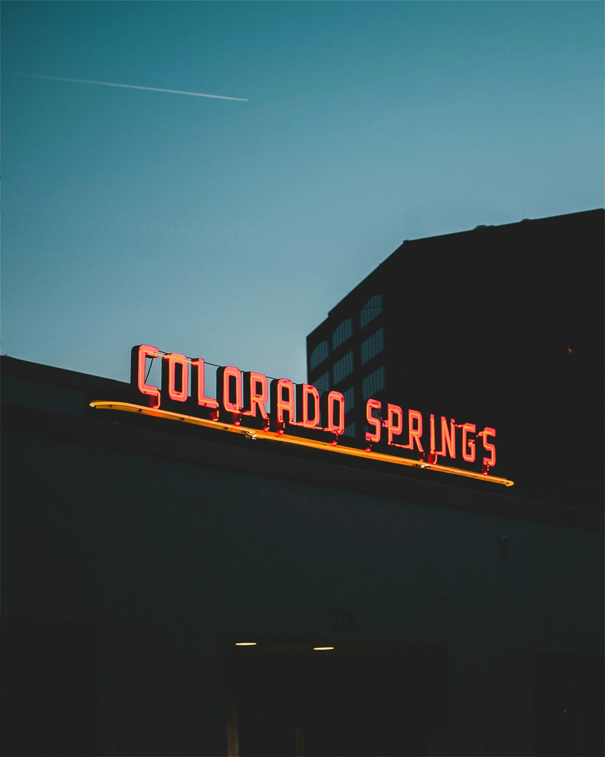 Illuminated Colorado Springs sign on a rooftop at dusk
