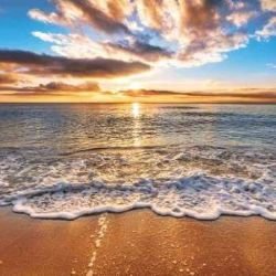 A picture of the sun setting over crashing waves on a beach