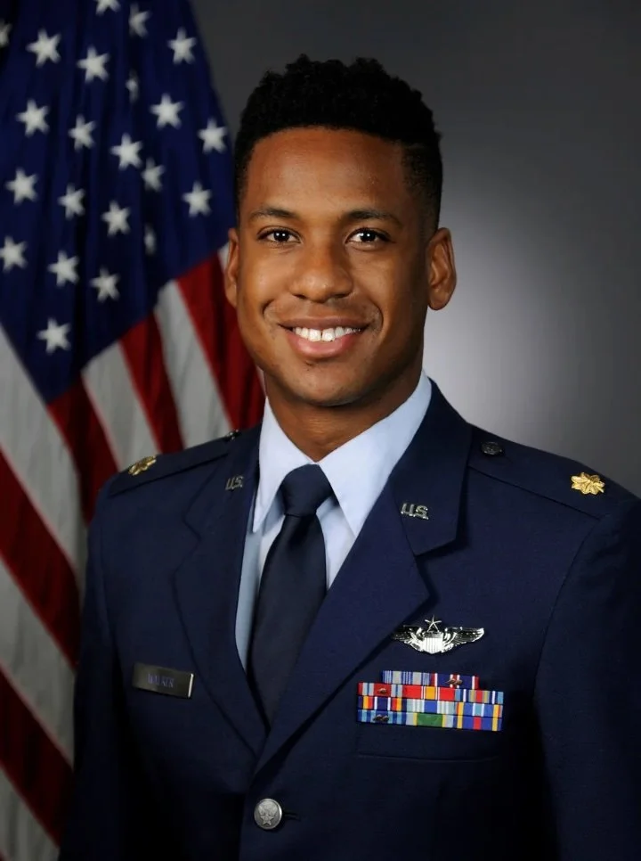 Major Daniel “Fuzz” Walker
Portrait of a smiling young male U.S. Air Force officer in uniform standing in front of U.S. flag.