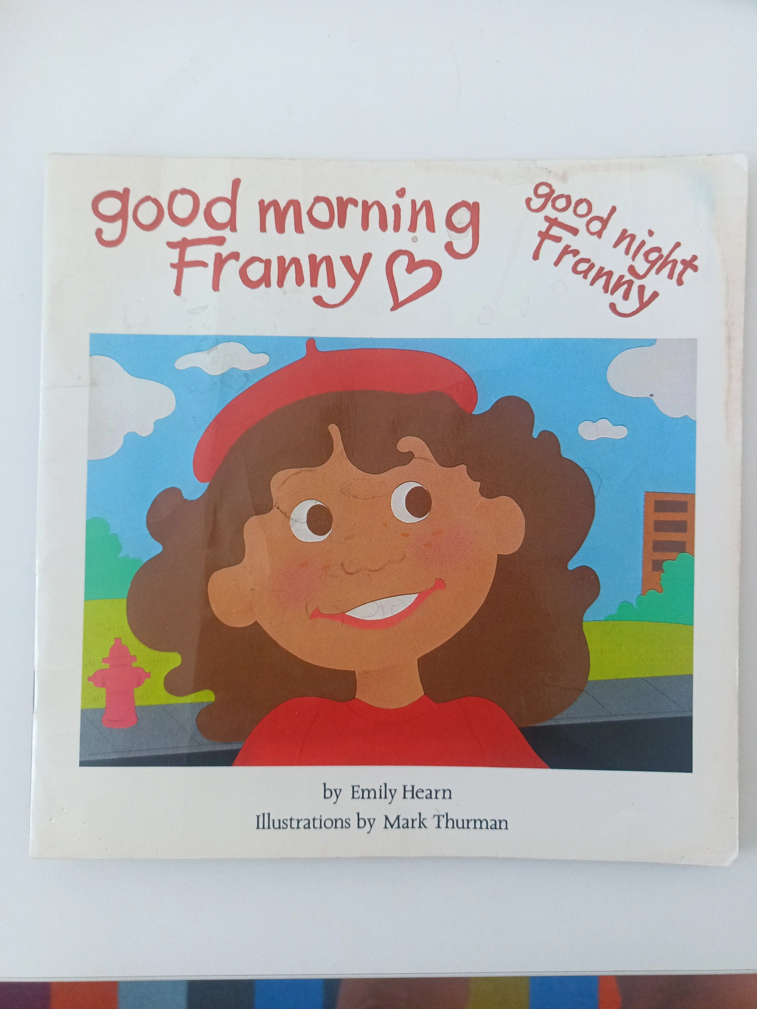 Illustrated book cover showing a smiling girl with curly brown hair and a red beret outdoors.