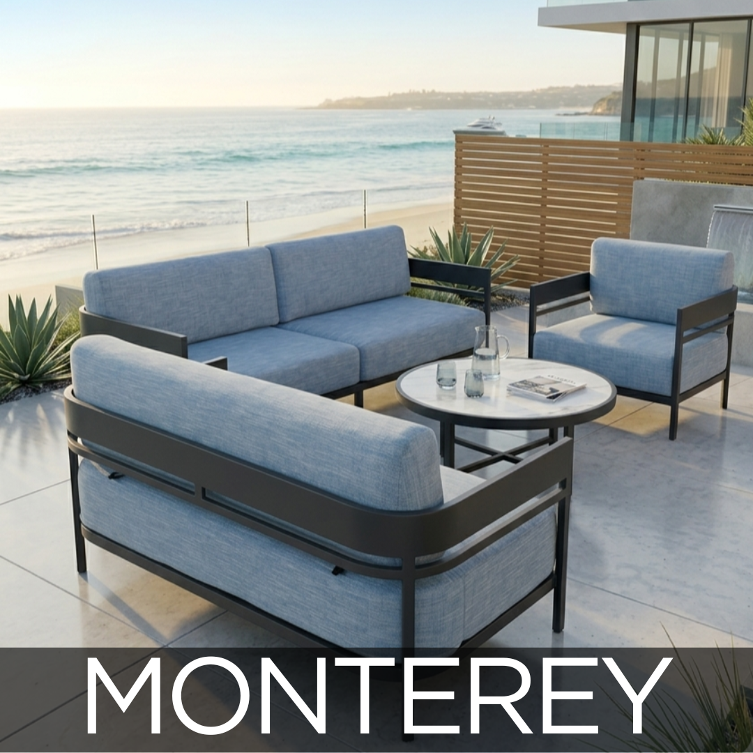 Outdoor terrace with blue cushioned seating, round table, palm trees, and view of distant landscape with blue sky in Monterey.