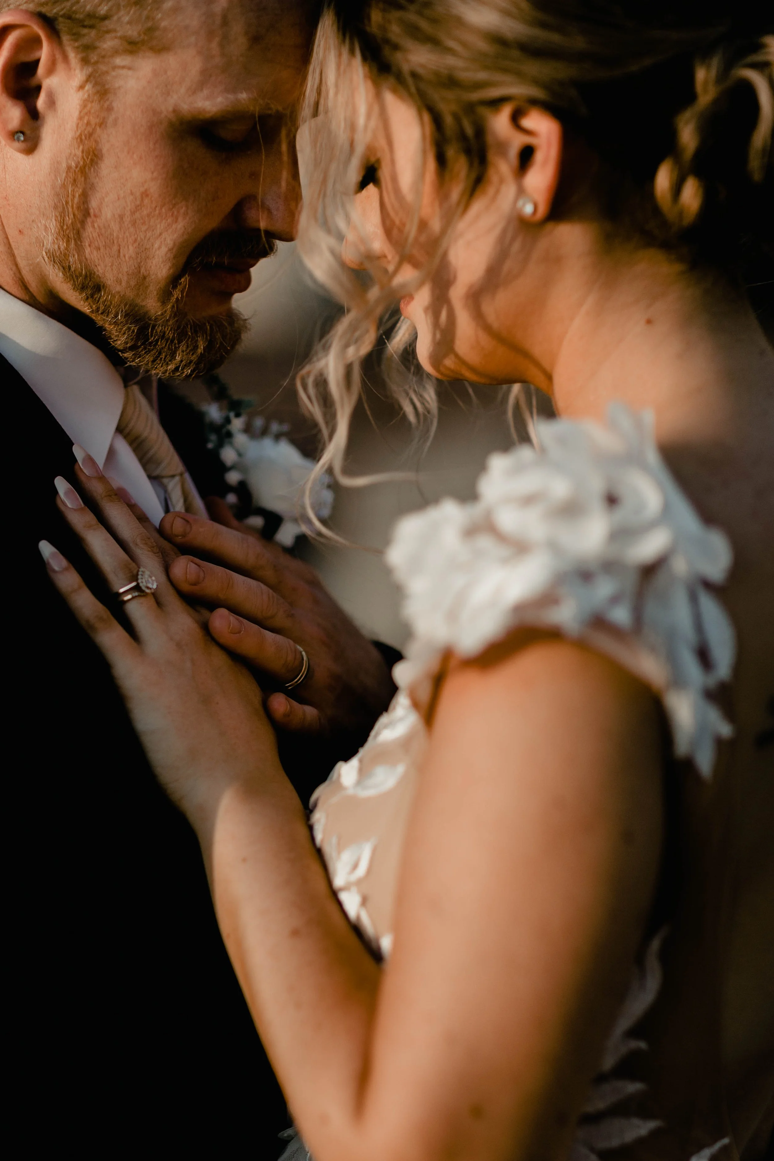 Close-up of a bride and groom sharing a tender moment at their wedding, with their foreheads touching and eyes closed, showing love and intimacy.