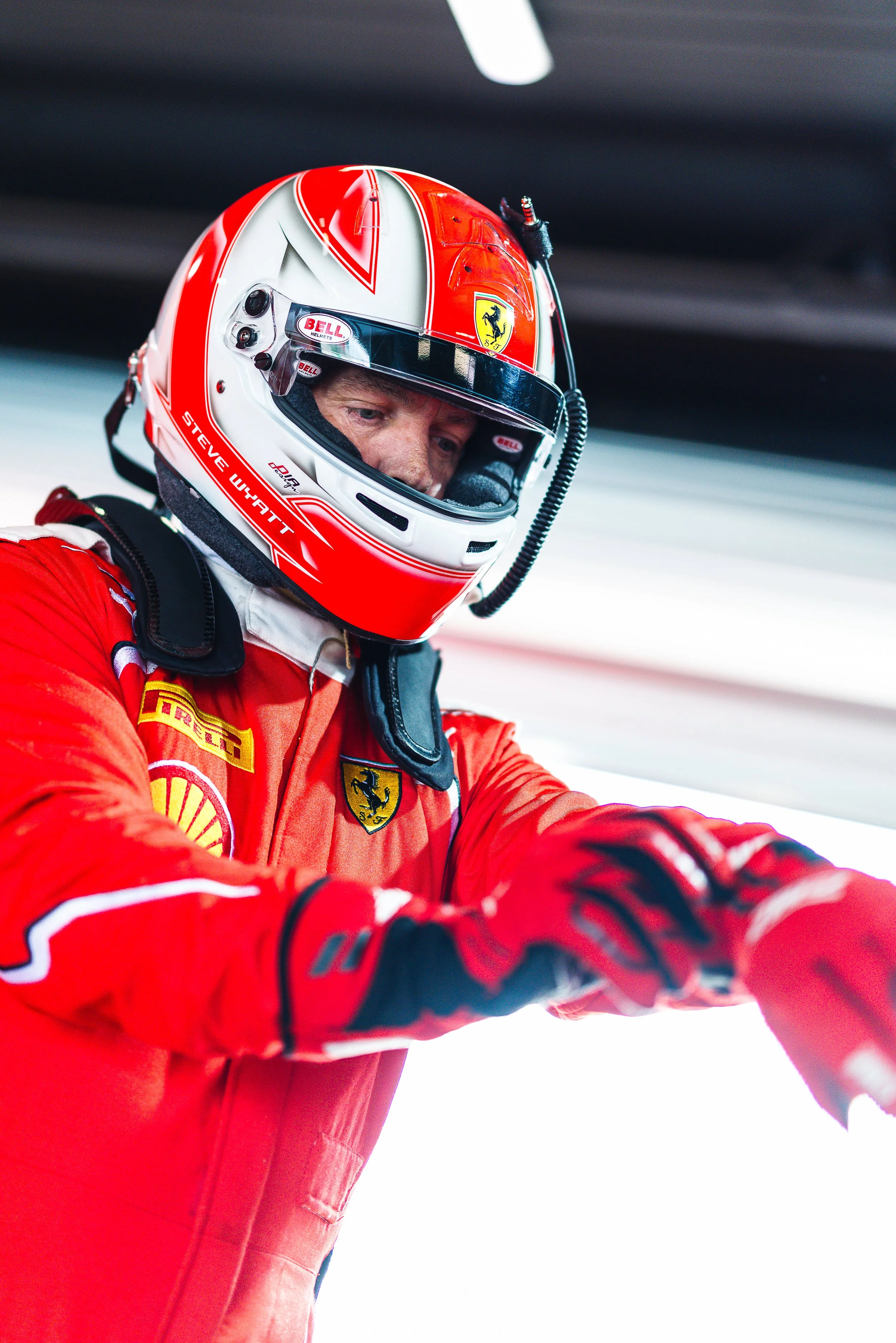 Steve Whyatt pulling on his gloves with his helmet on, captured from a low angle during the 2025 GT World Challenge Australia season.