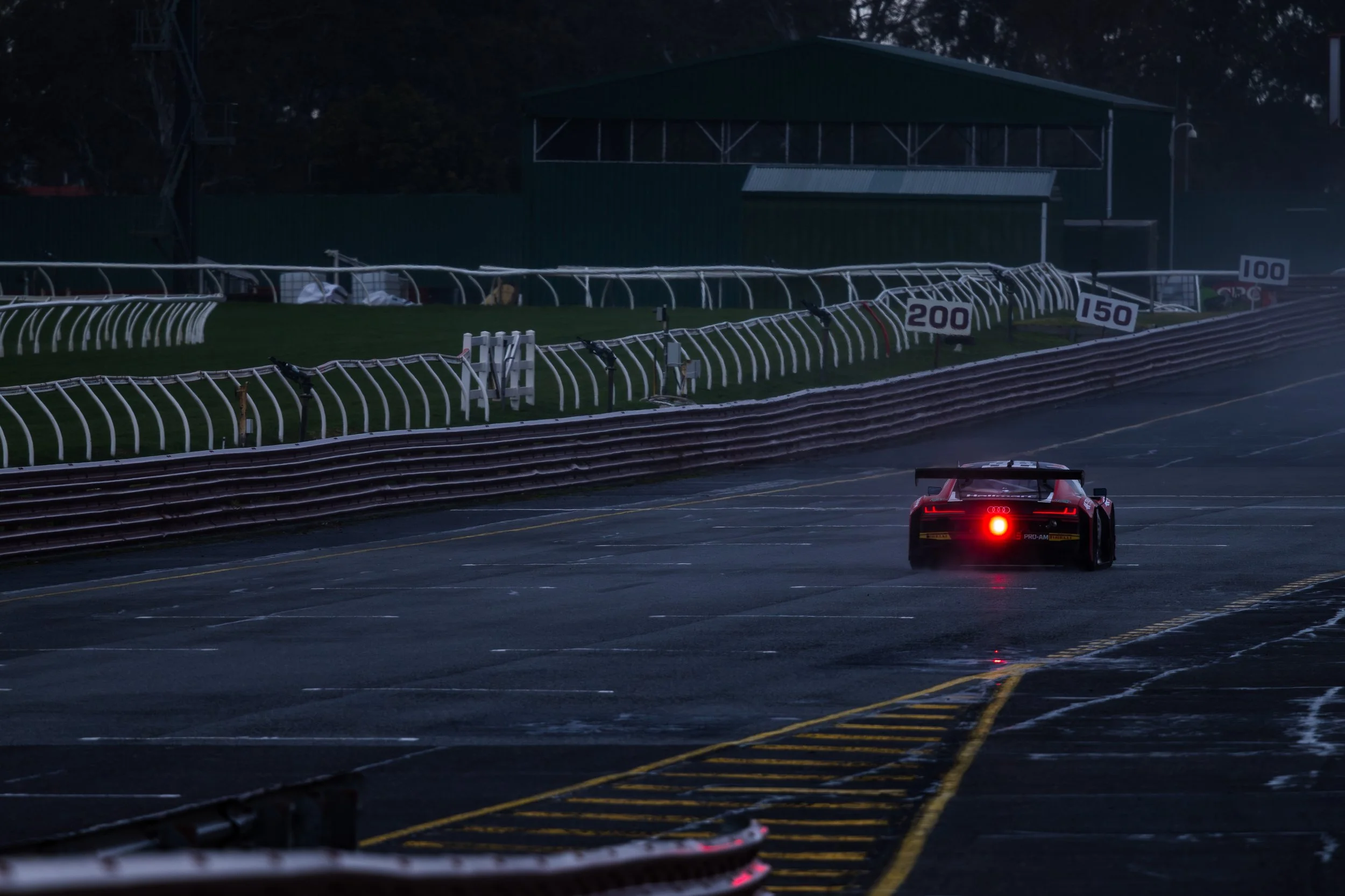 A moody dark image of a Melbourne Performance Centre Audi R8LMS throwing water spray at the Sandown Raceway GT World Challenge Australia event.
