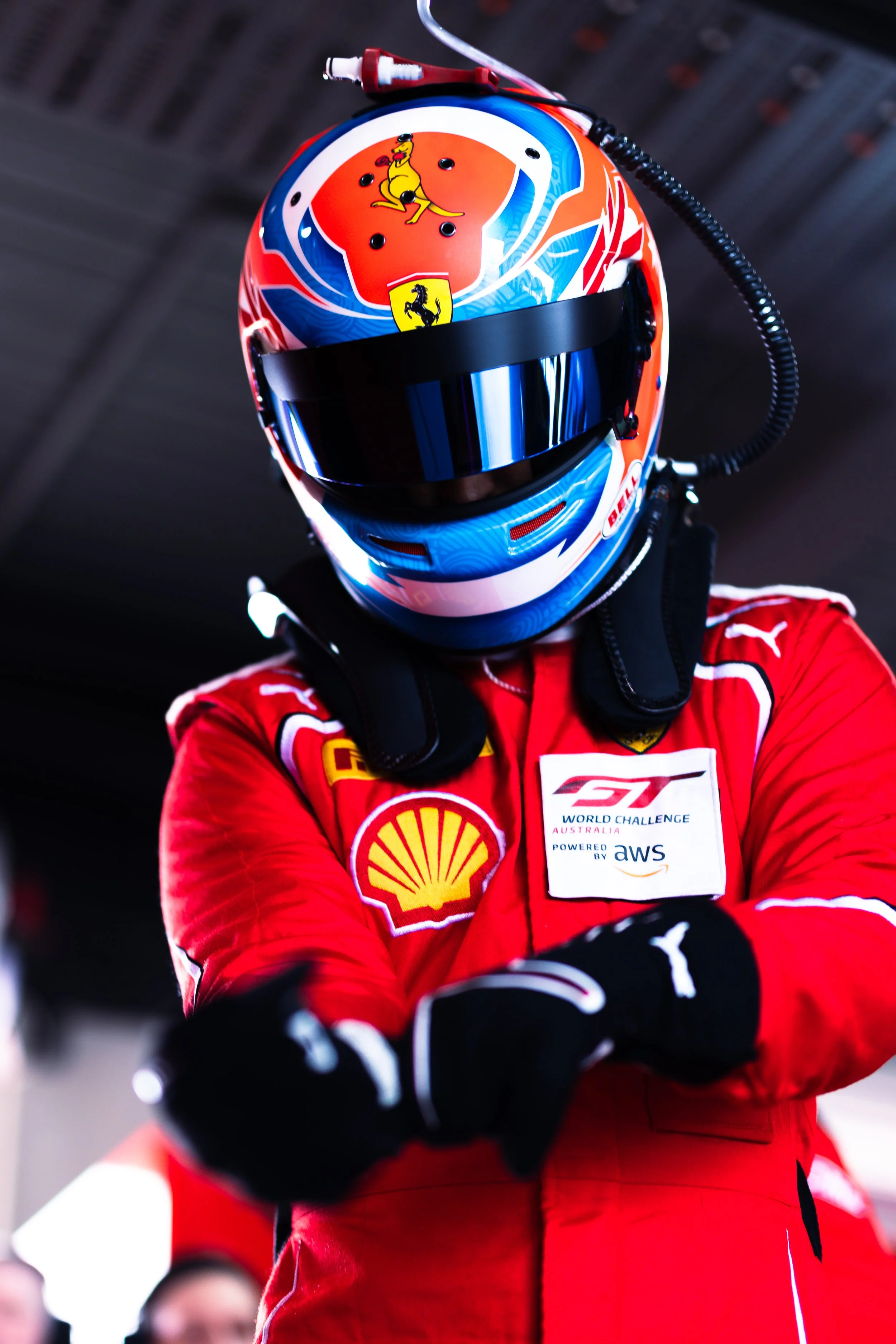 Jordan Love pulling on his gloves with his helmet on, captured from a low angle during the 2025 GT World Challenge Australia season.
