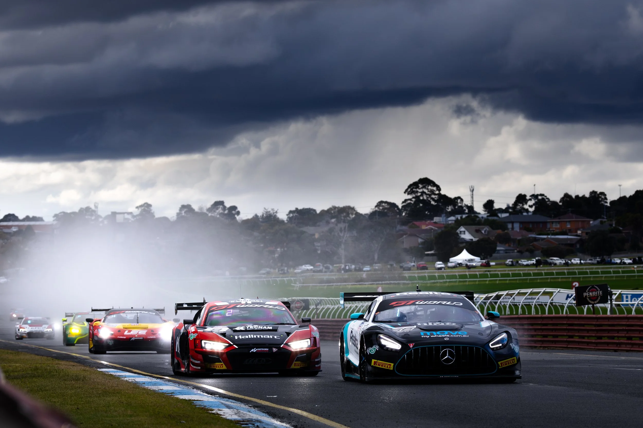 The start of a race at Sandown raceway as Jayden Ojeda leads into turn 1 with rain in the background at the 2025 GT World Challenge Australia round.