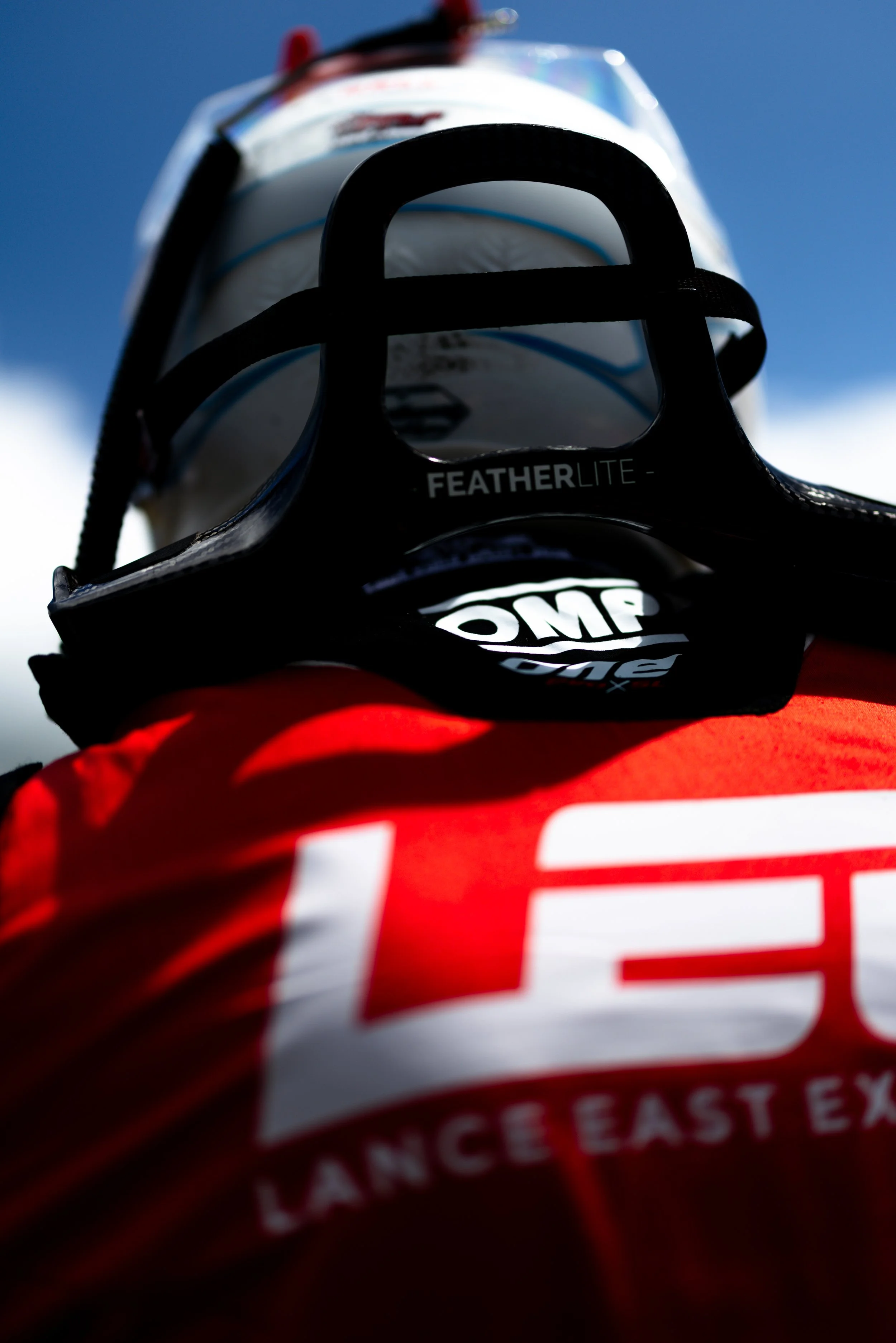 Close-up of Jaxon Evans’ helmet and HANS device with Arise Racing GT branding on the back of his race suit.