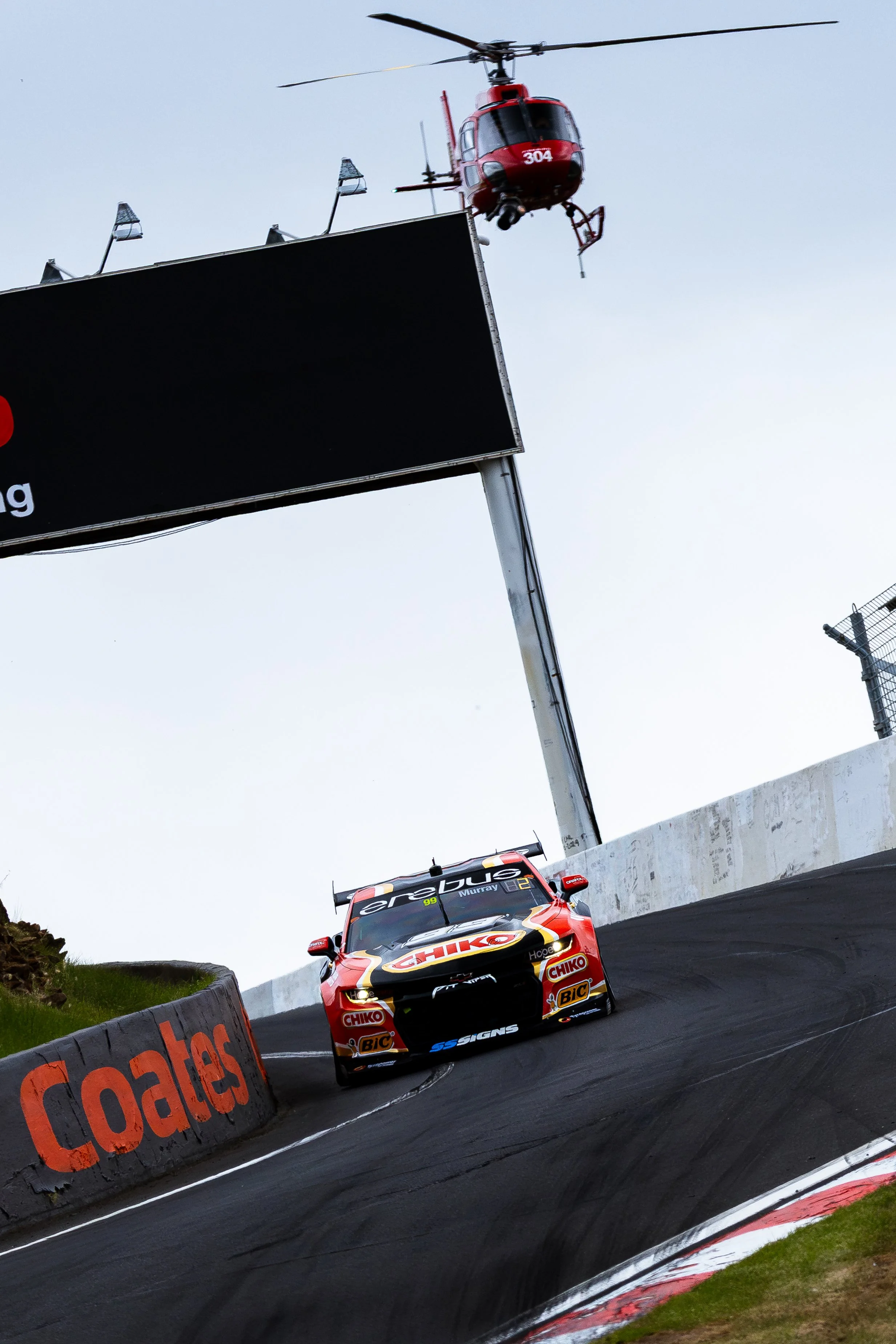 Erebus Motorsport’s ‘Chicko’ Supercars Camaro ZL1 driven by Cooper Murray and Jobe Stewart passing through the Esses with a TV helicopter in the background.