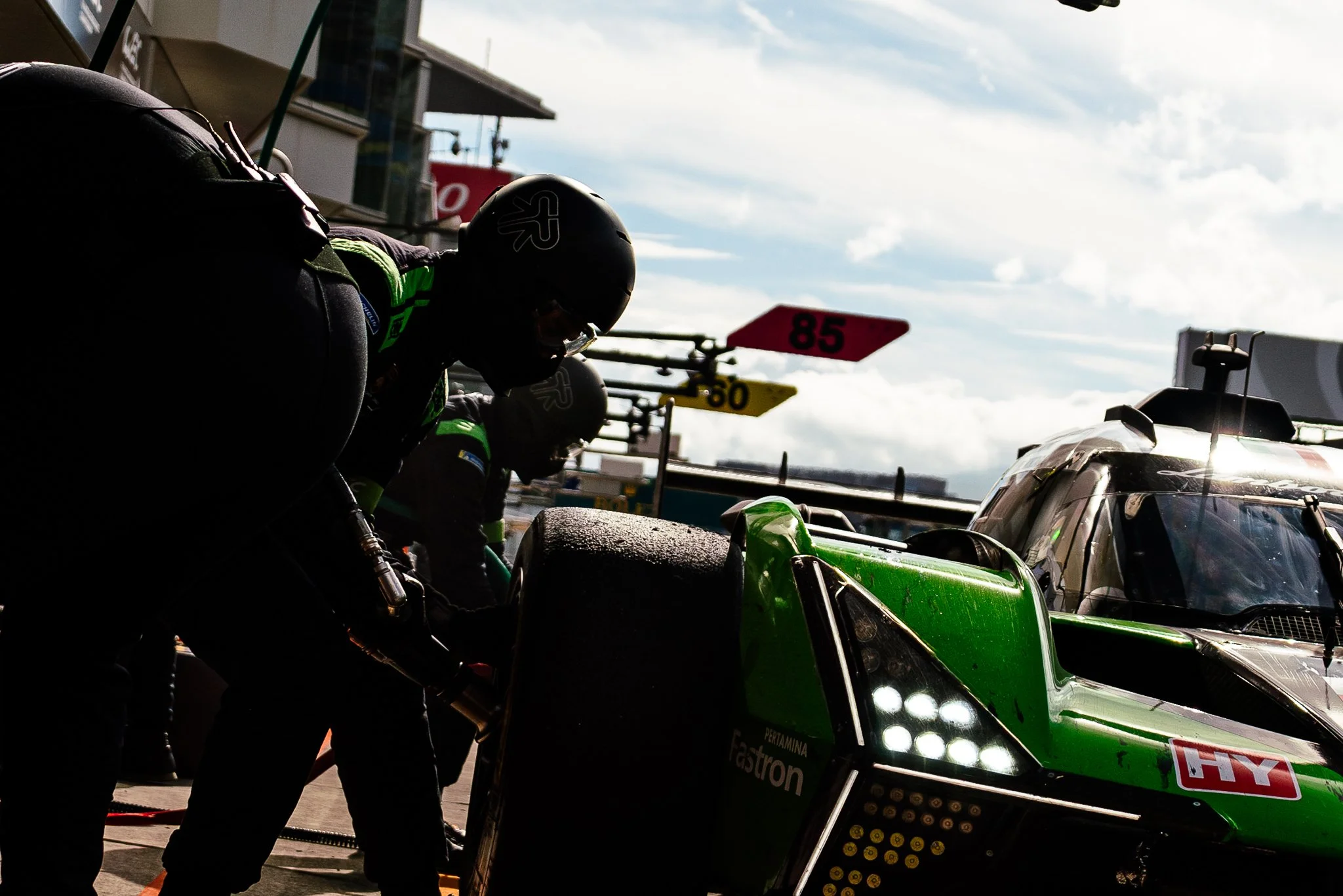Lamborghini mechanics service the Hypercar in the pit lane, with a mechanic fitting a wheel during the 2024 World Endurance Championship round at Fuji Speedway.