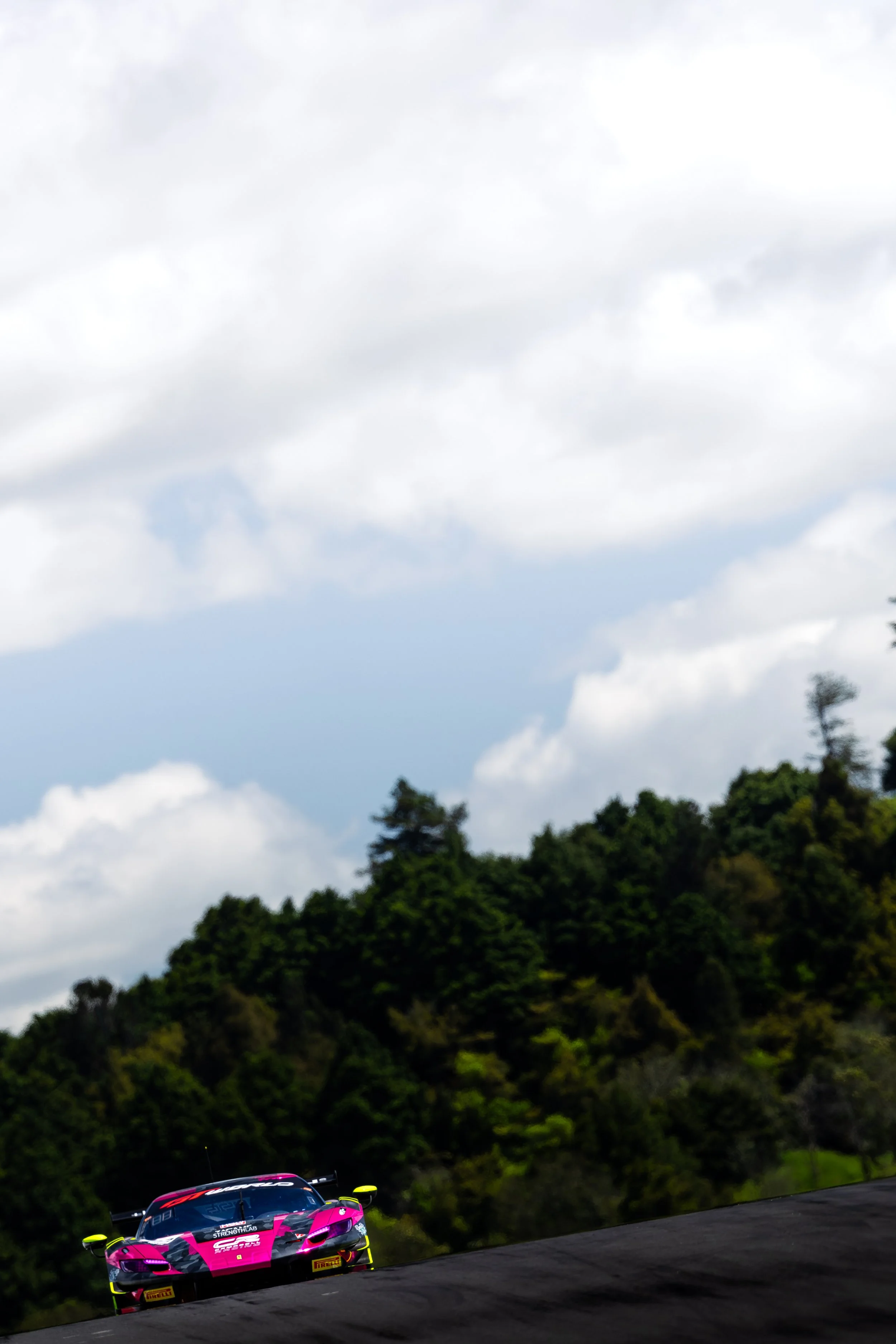 Zagame Motorsport Ferrari 296 GT3 cresting the hill with trees in the background at Hampton Downs Raceway during the 2025 GT World Challenge Australia season.