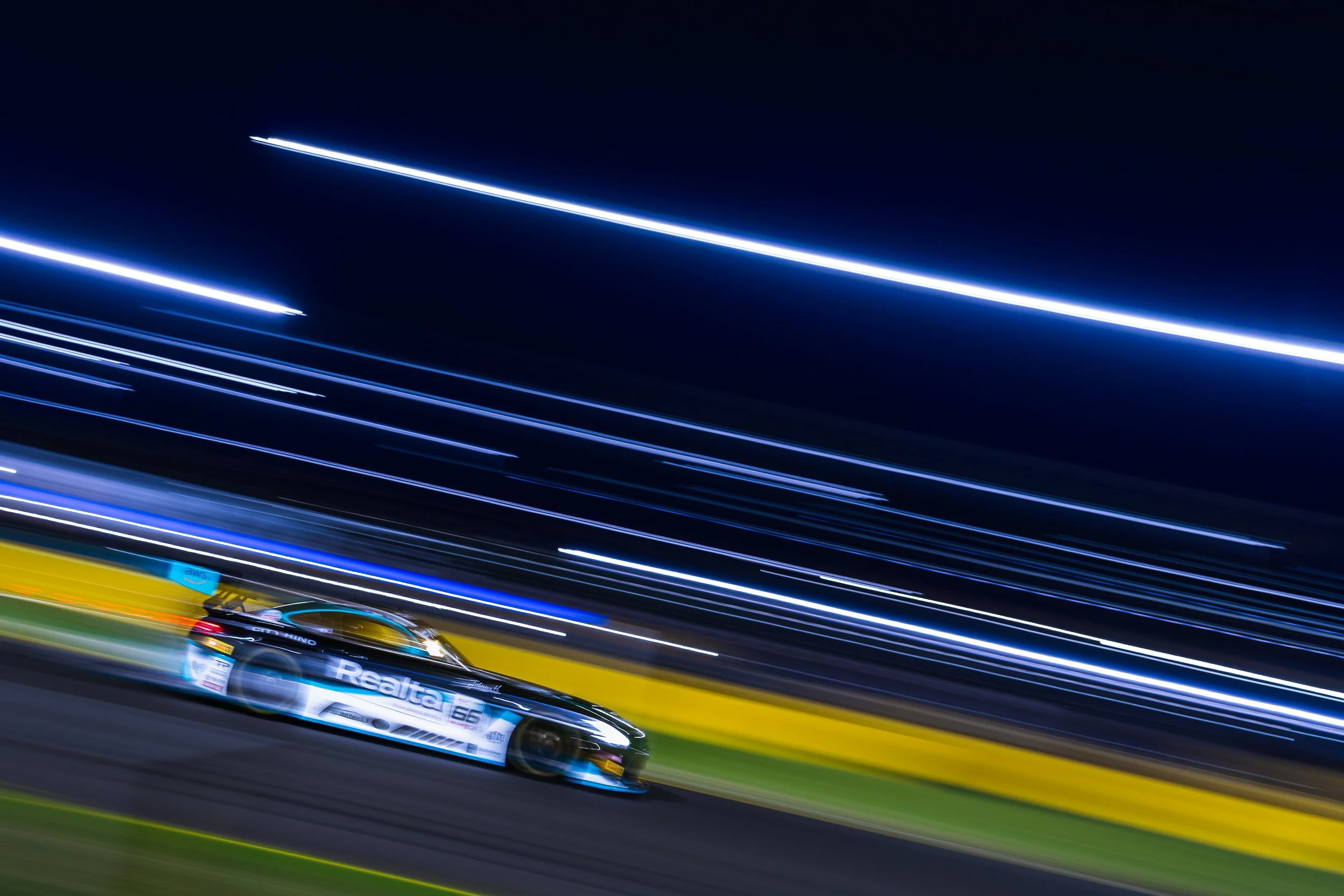 Tigani Motorsport s Mercedes AMG GT3 race car captured by a whip-pan at a night race during the 2024 Sydney Motorsport Round of the GT World Challenge Australia round.