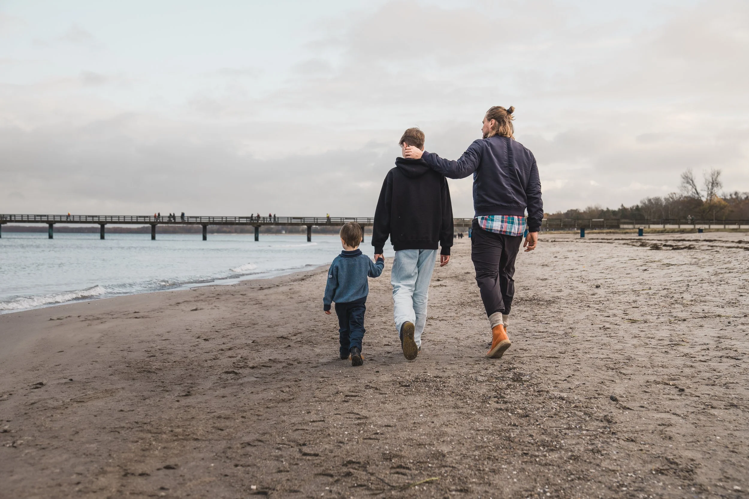 Vater mit Söhnen beim Strandspaziergang an der Ostsee