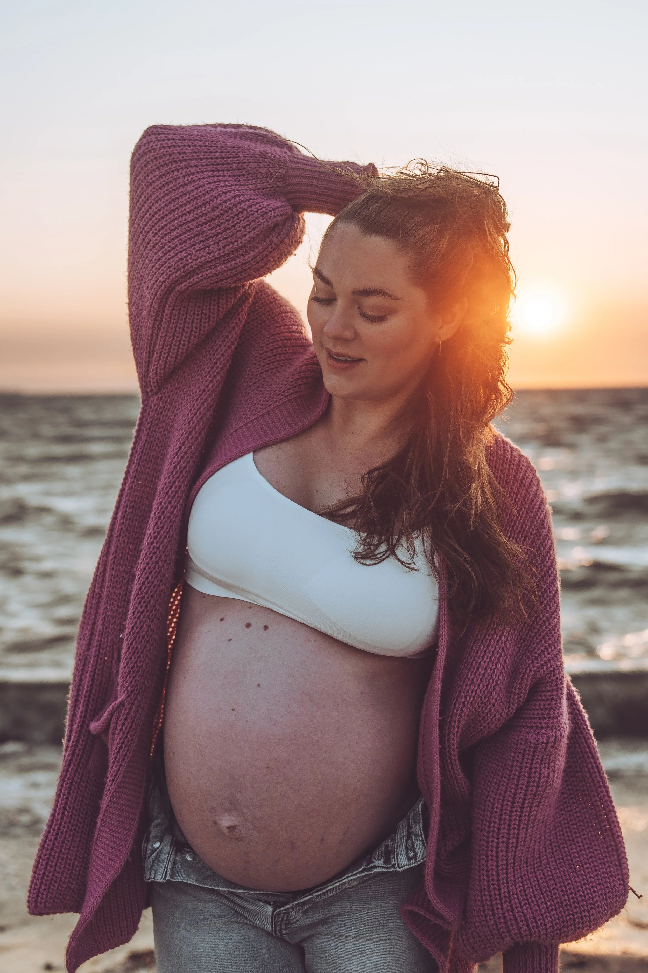 Porträt einer hübschen jungen Frau an der Ostsee während der goldenen Stunde am Horizont