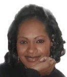 Close-up of a woman with dark curly hair smiling and resting her chin on her hand.