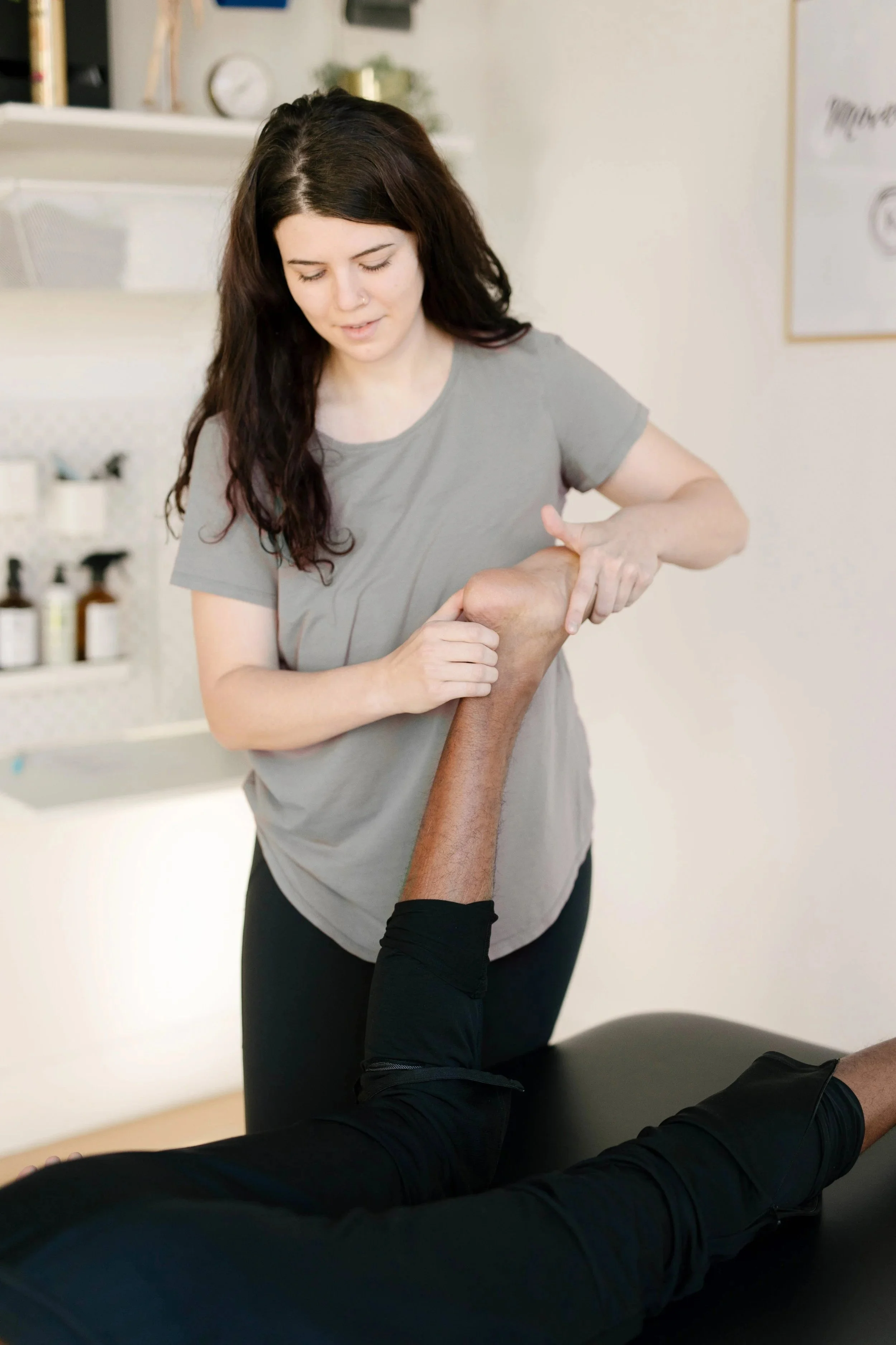 A woman receiving physical therapy on her leg from a therapist in a clinical setting.