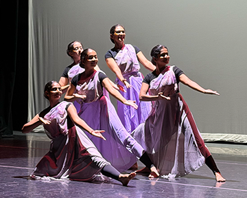 A group of five dancers performing on stage.