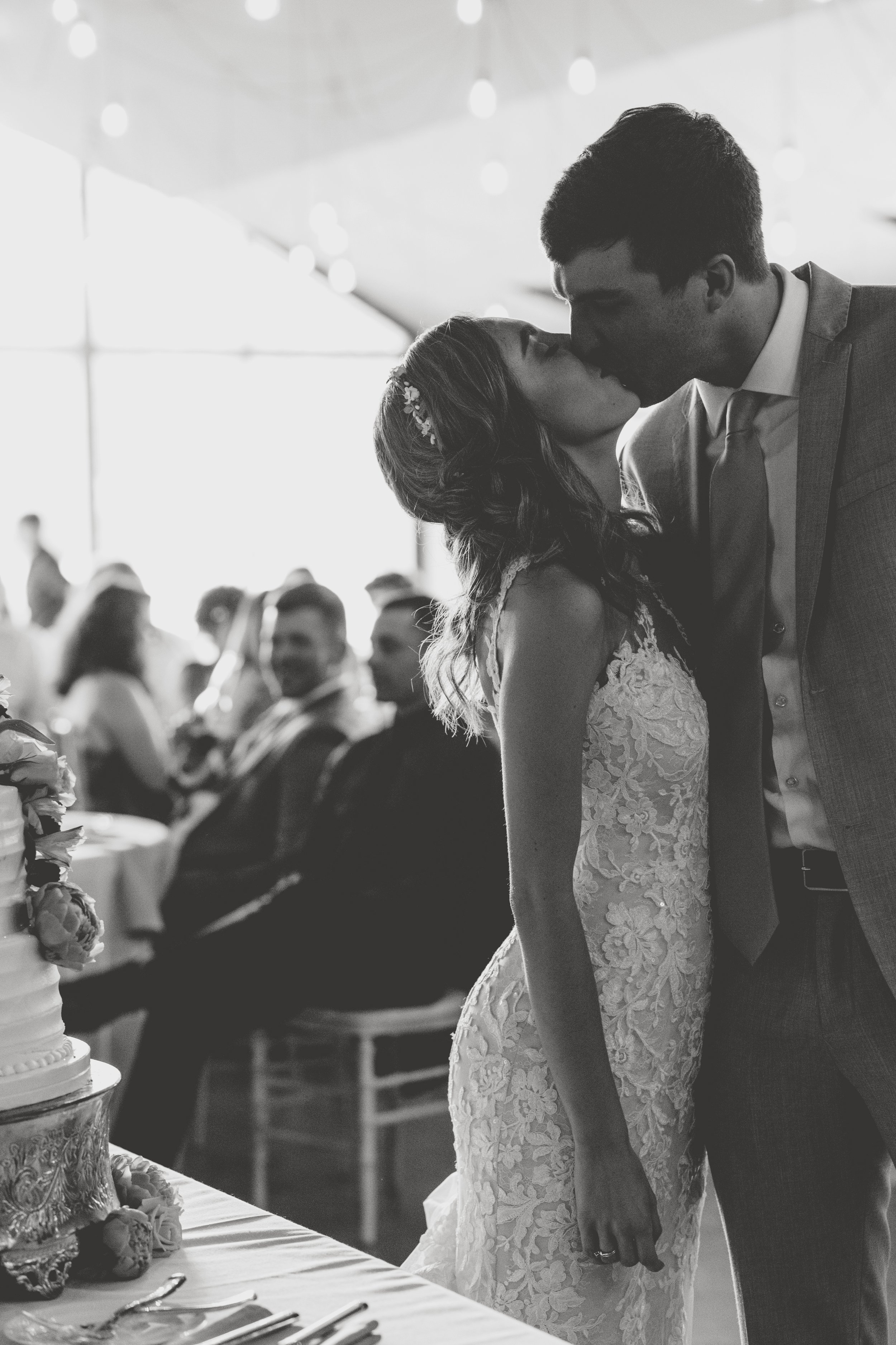 Under a moonlit sky, the bride and groom share a tender kiss, marking the end of an unforgettable evening as the world around them dissolves into a timeless black and white landscape. This enchanting photograph encapsulates the powerful emotions of t