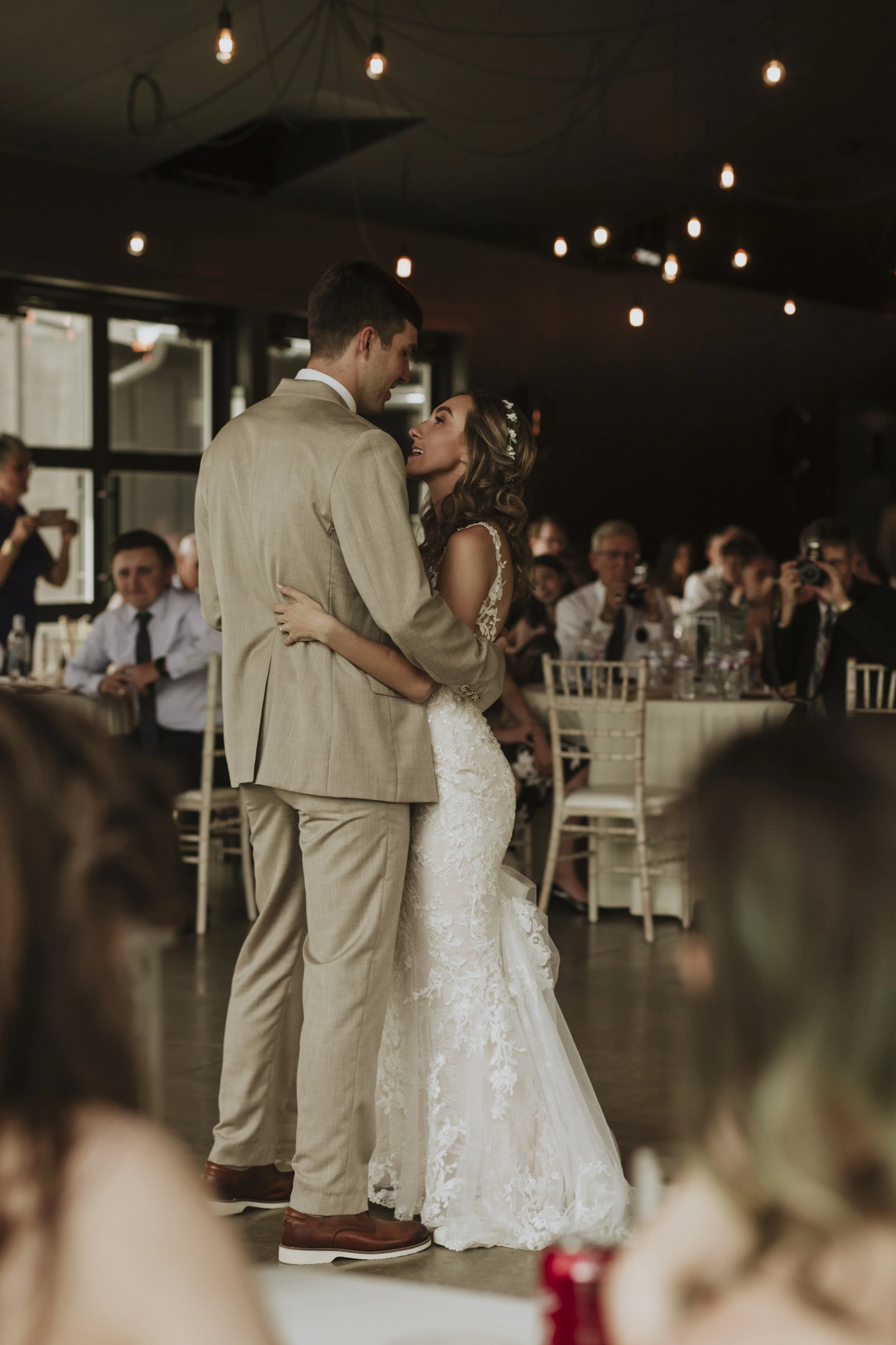 As the soulful melody fills the air, the bride and groom tenderly embrace one another during their first dance as a married couple. The photograph captures the intimacy of the moment, with the couple's adoring gazes and gentle smiles reflecting the d