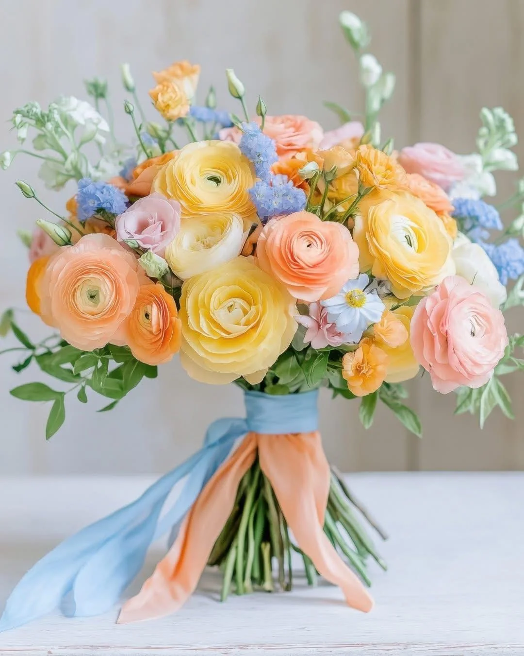 💕💛 This bouquet doesn't whisper
"summer" &mdash;it sings it. A playful mix of buttercream ranunculus, tangerine blooms, and delicate sky-blue fillers brings joy to every stem. Ideal for bold brides with a soft spot for pastels.
