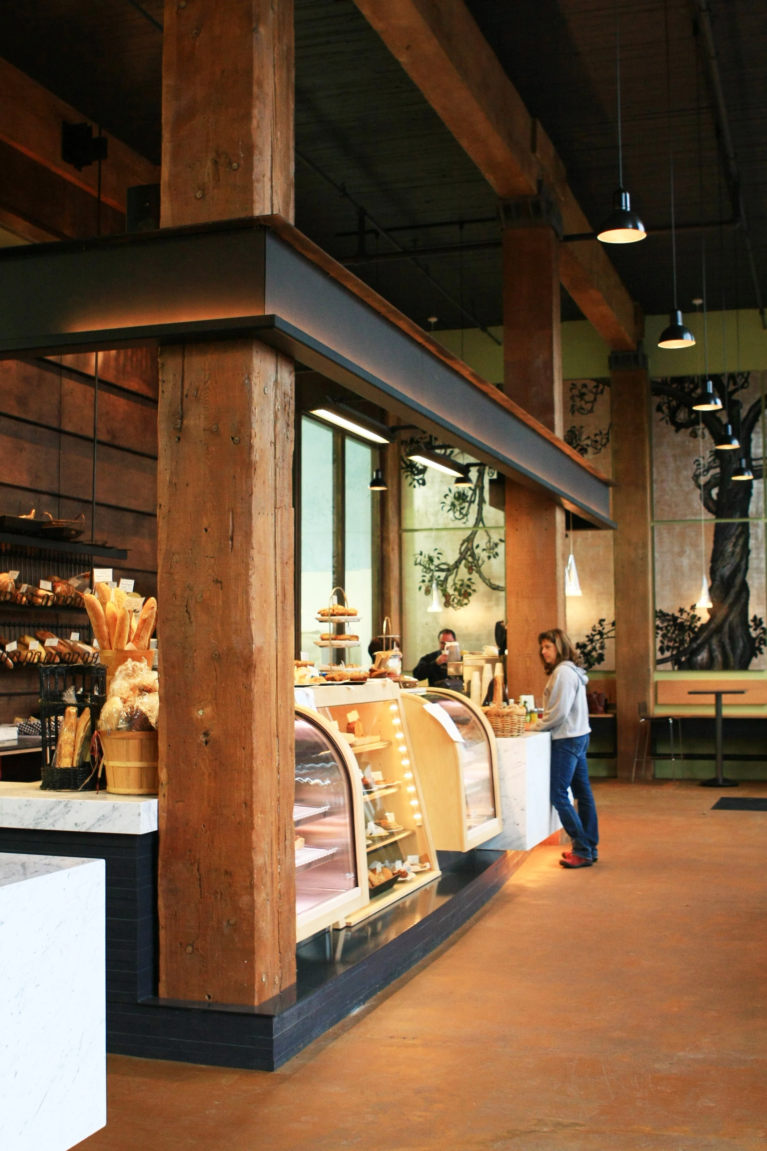 Interior of a bakery with wooden beams and a counter displaying pastries.