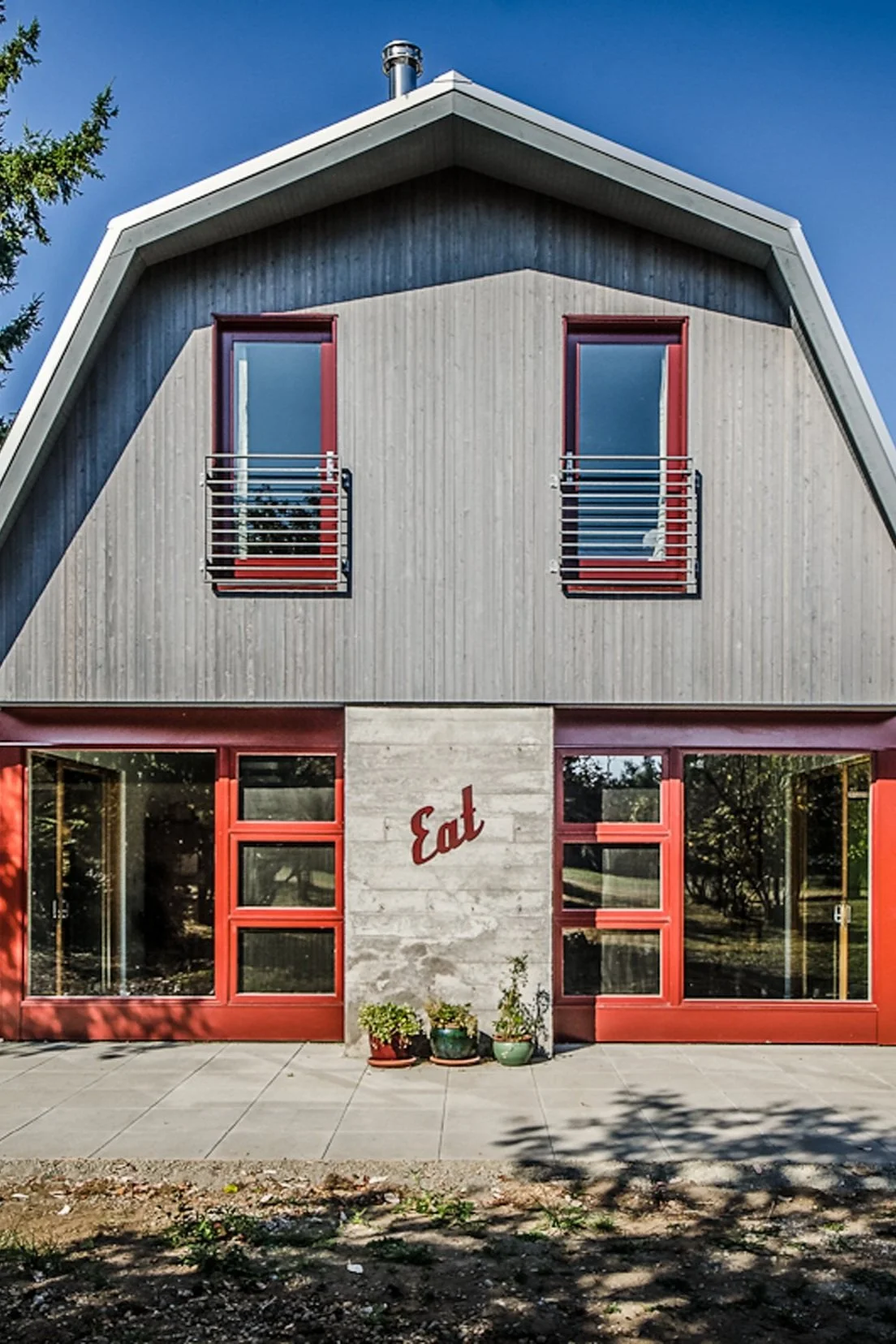 Modern house exterior with red windows and "Eat" sign