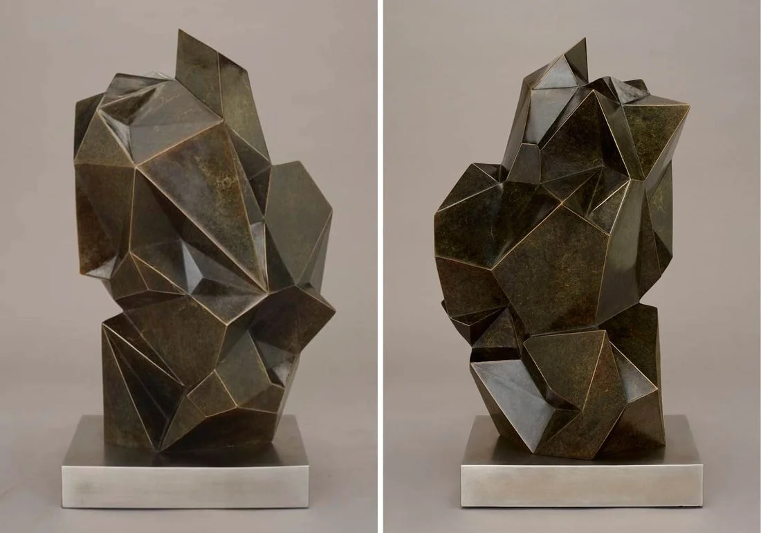 Abstract metallic geometric sculpture with irregular polygonal shapes mounted on a rectangular base.