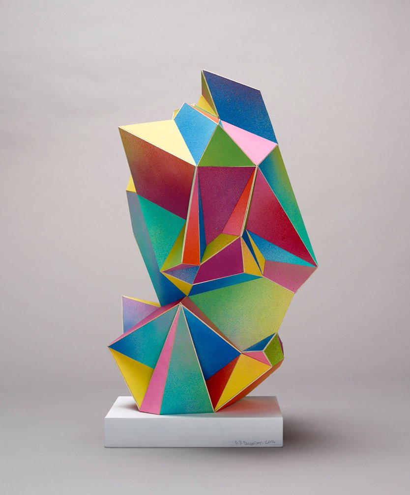 Colorful geometric paper sculpture on a white base.
