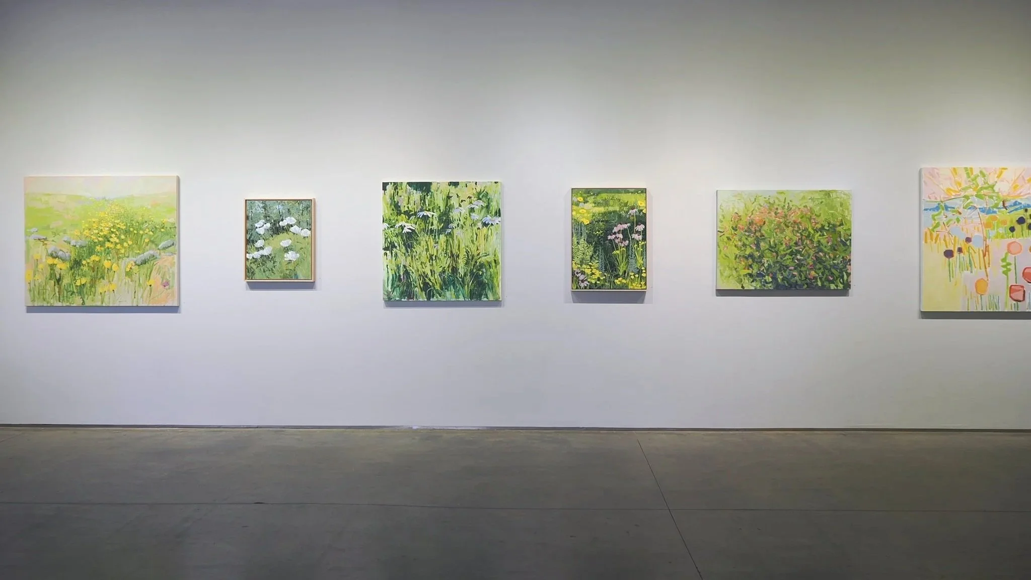 paintings of flowers hanging on a gallery wall