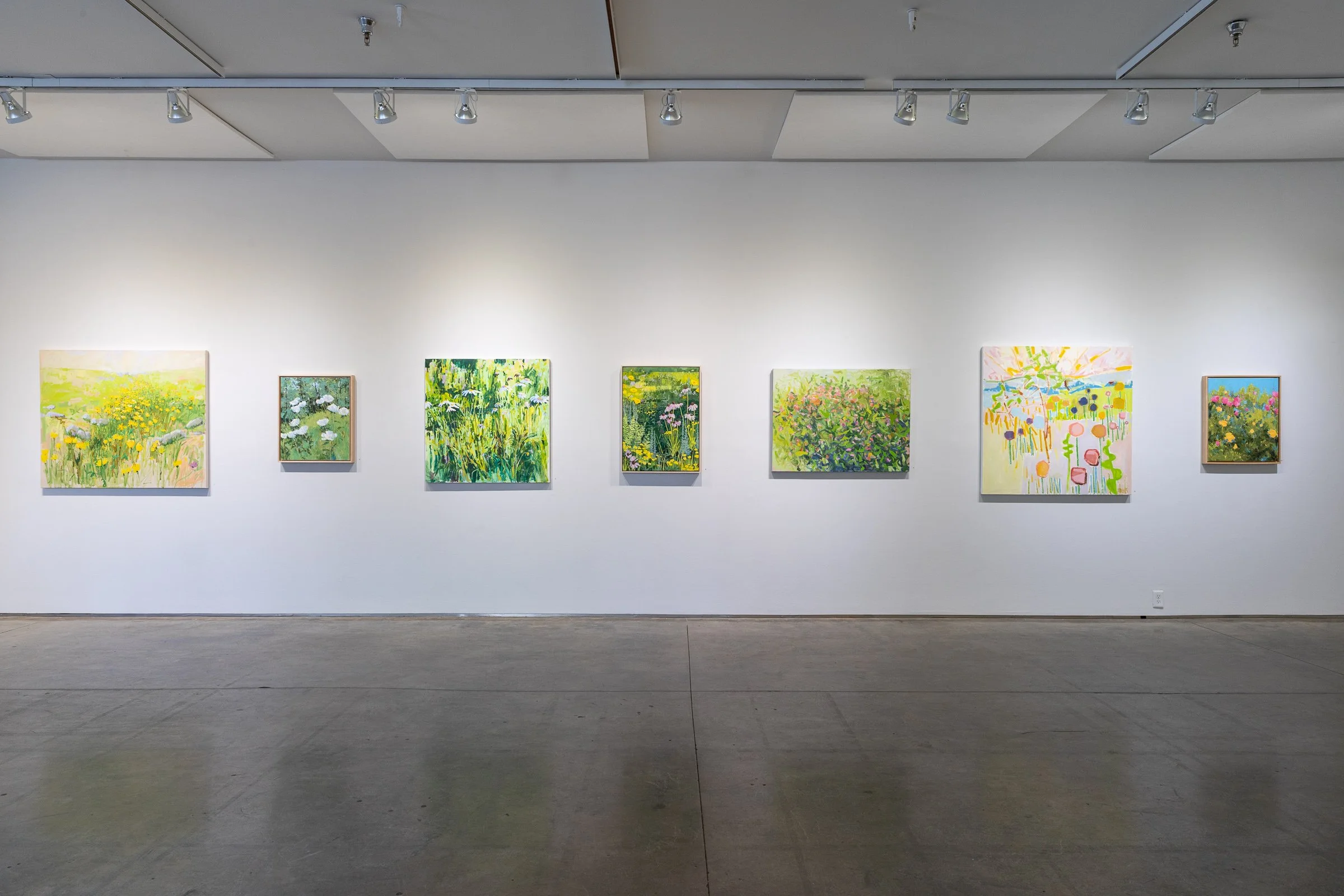 paintings of flowers hanging on a gallery wall