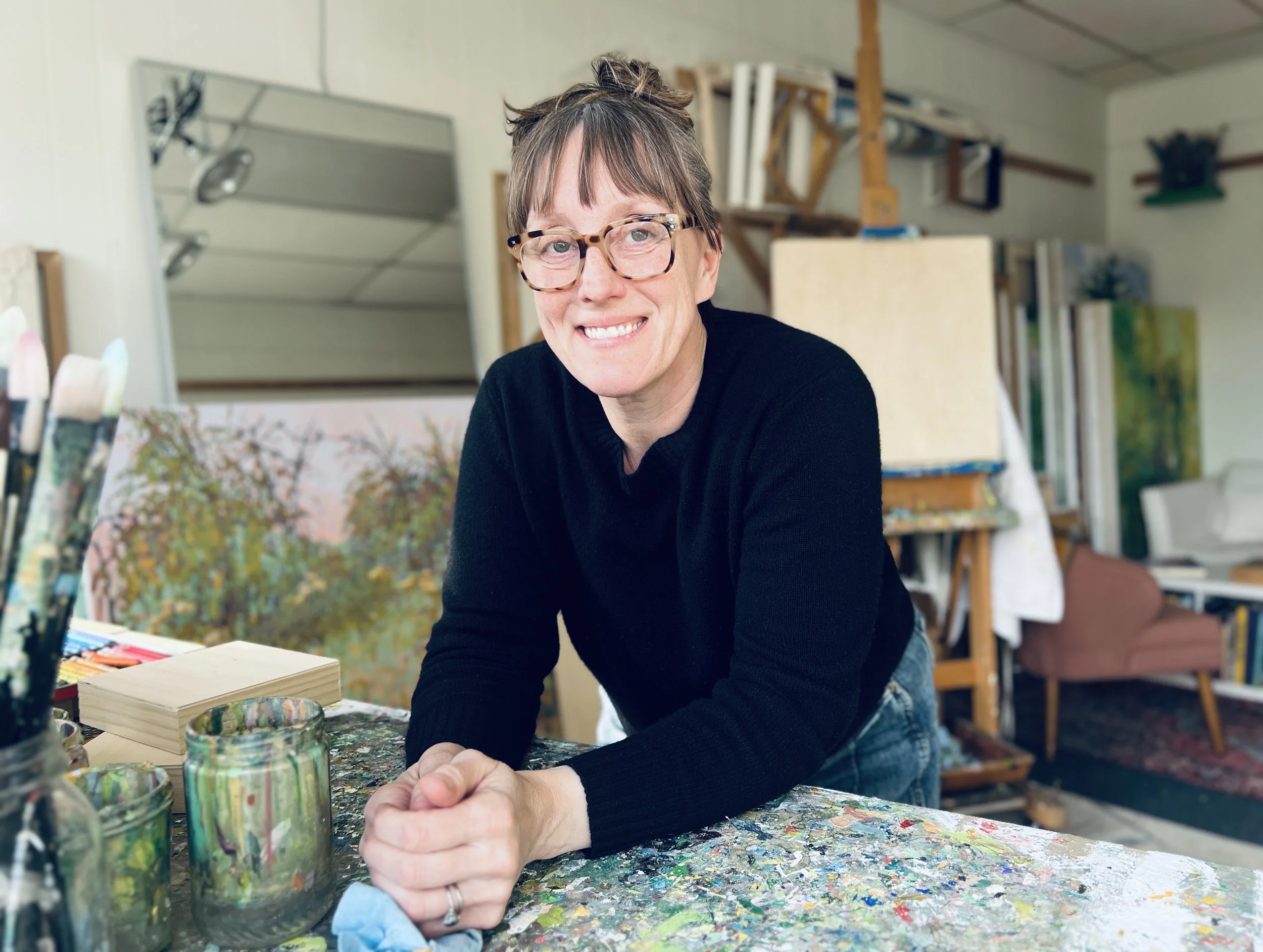 Artist leaning on a table covered in paint.