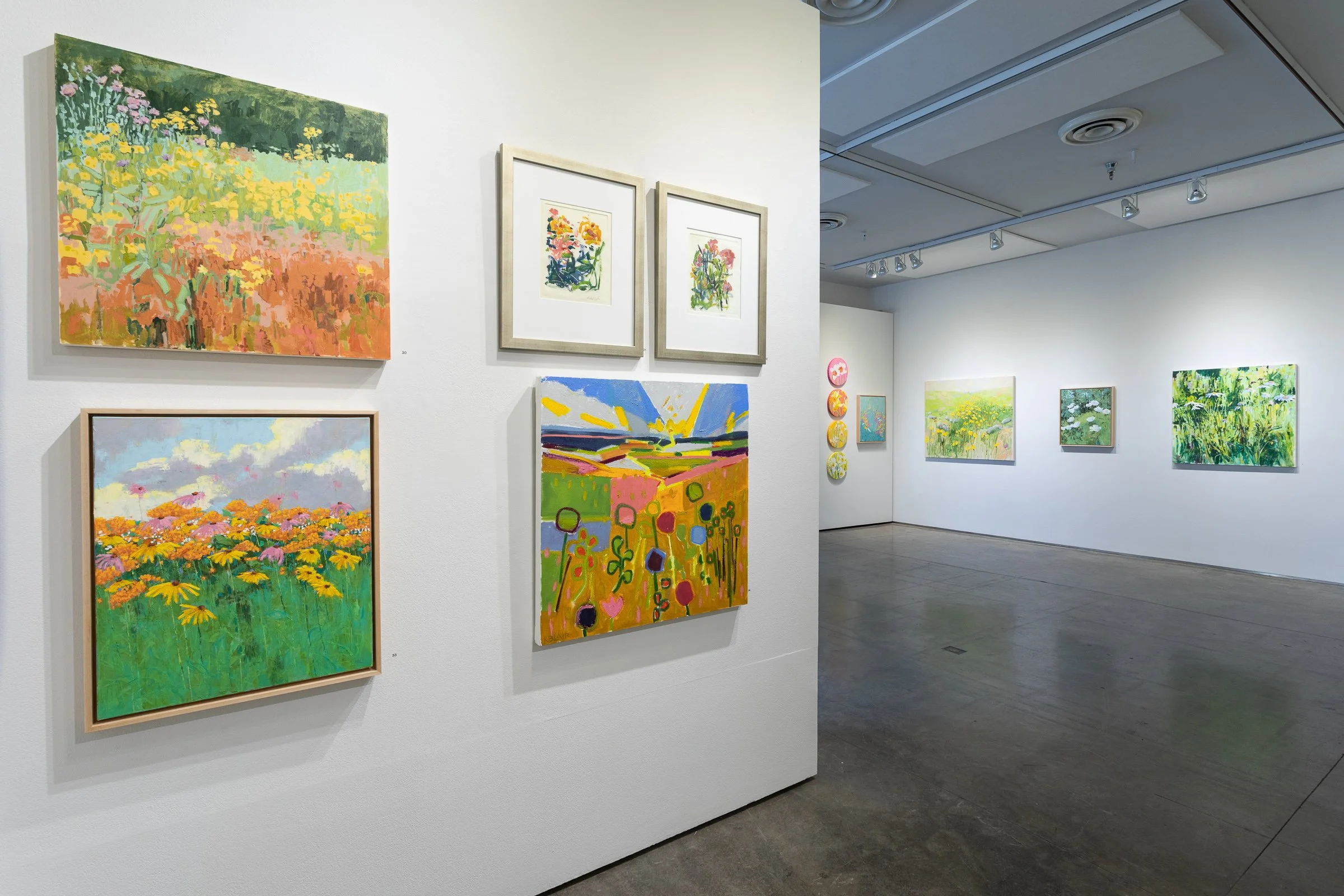 Floral paintings hanging on a gallery wall.