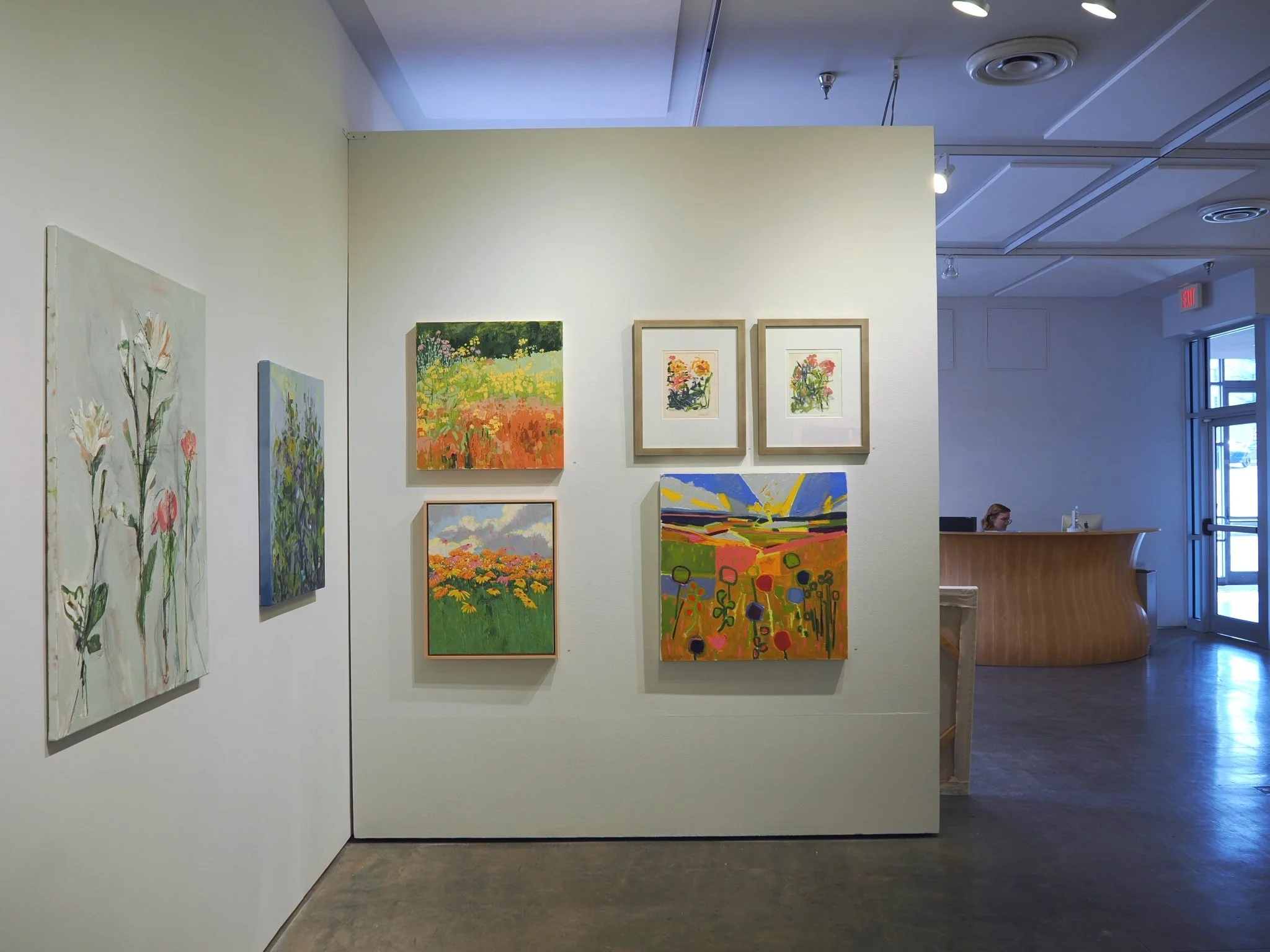 Floral paintings hanging on a gallery wall.