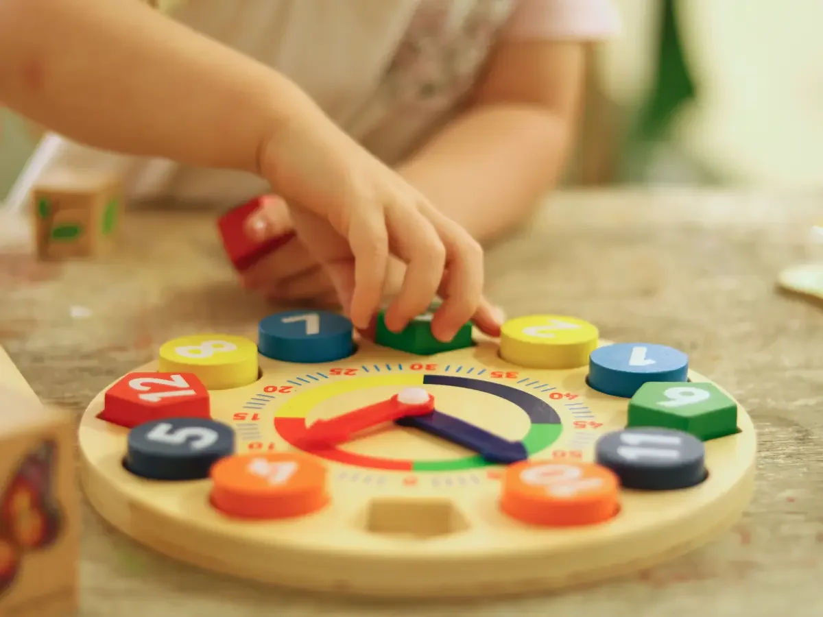 Child placing a puzzle piece into a puzzle of a clock face
