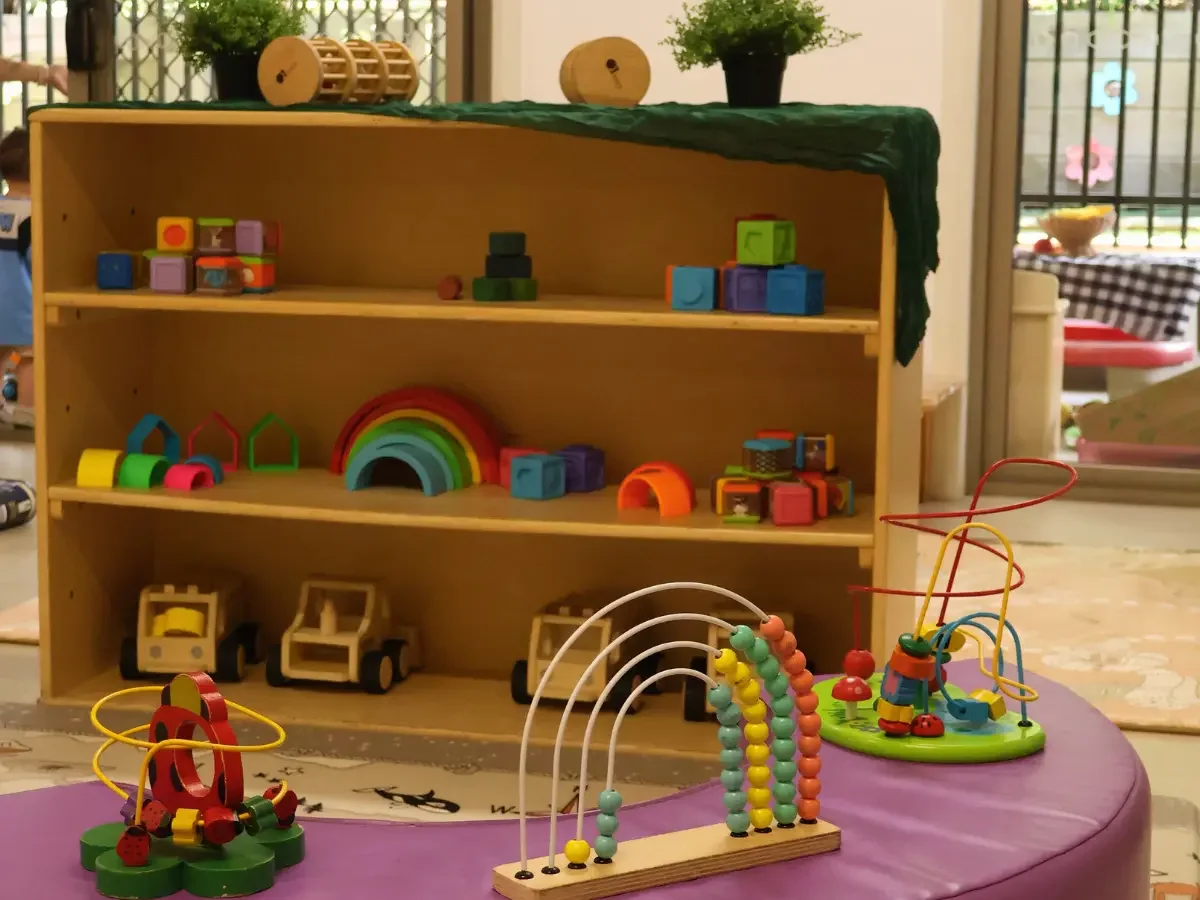 Indoor play area with shelves displaying a collection of blocks, trucks and wooden bead mazes