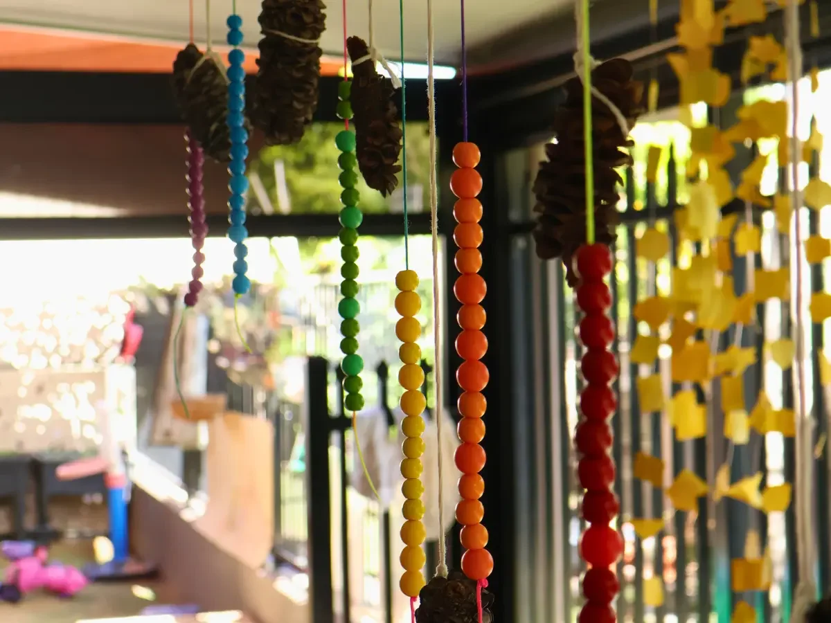Colorful hanging decorations made of beads, pinecones, and small objects.