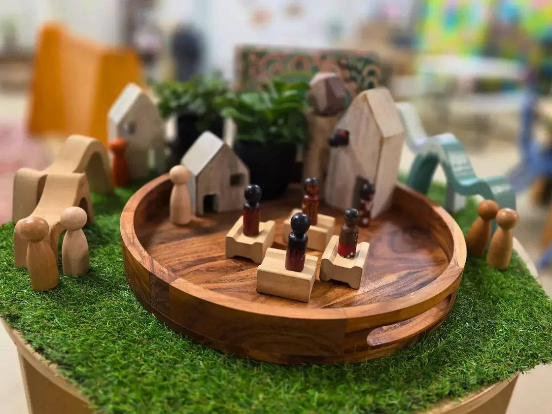 Wooden peg people and houses on a wooden tray for play