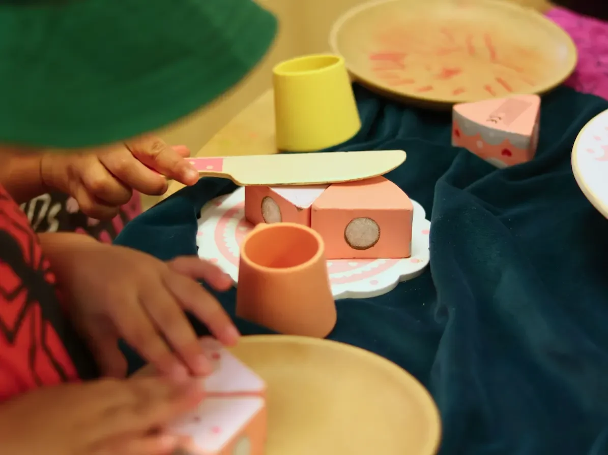 Children playing in home corner pretending to ice a cake