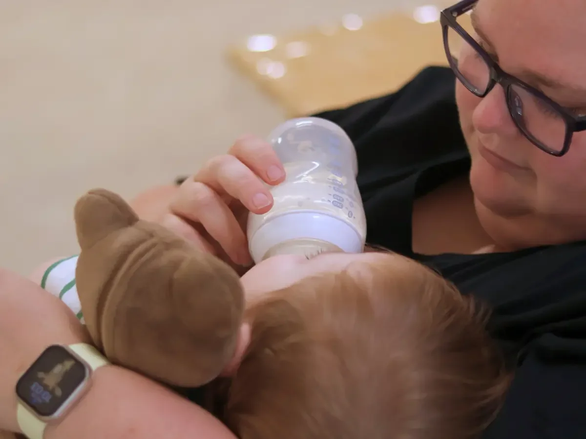 Educator bottle feeding and cuddling a baby