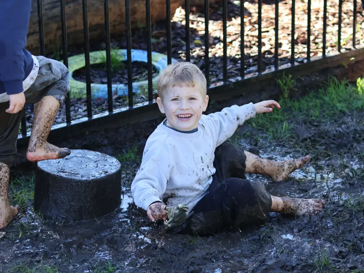 Smiling child playing in the mud