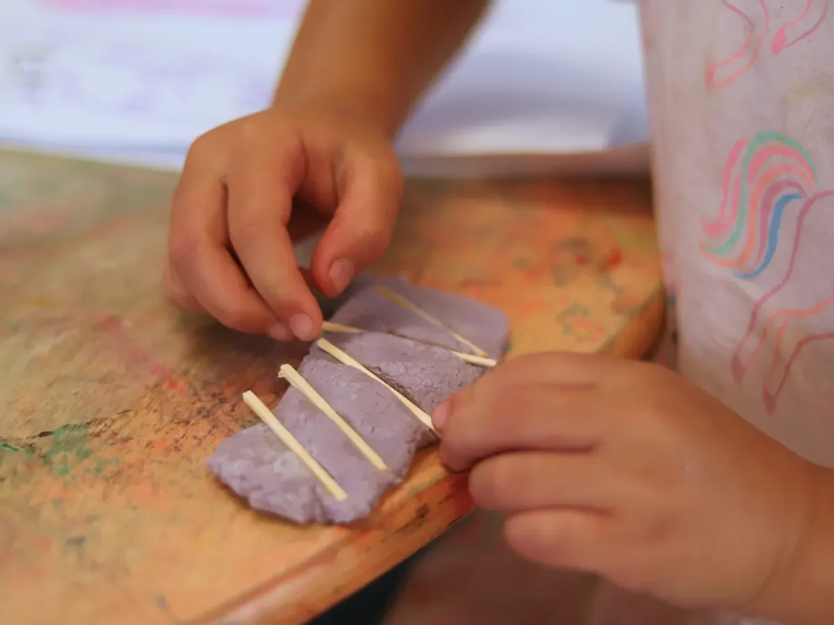 Child pressing matchsticks into playdough