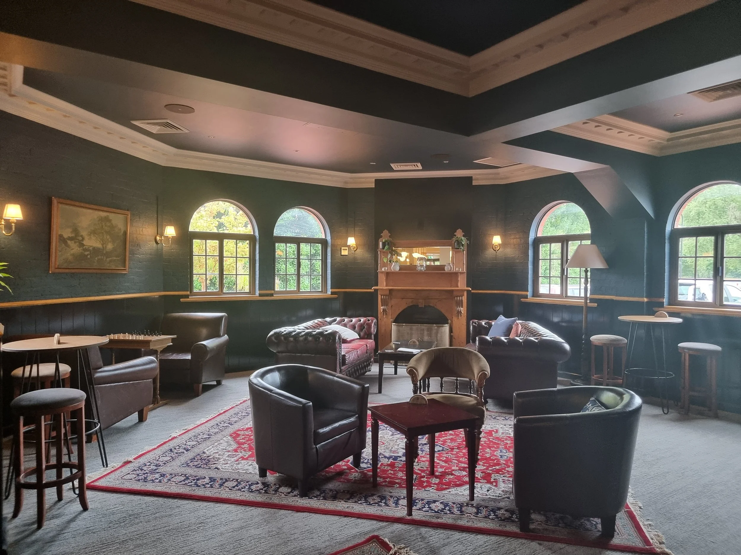 Cozy lounge with leather armchairs, a patterned rug, and windows letting in natural light.