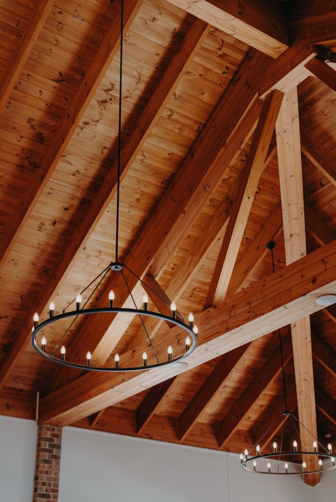 Wooden ceiling with exposed beams and circular chandelier lights.