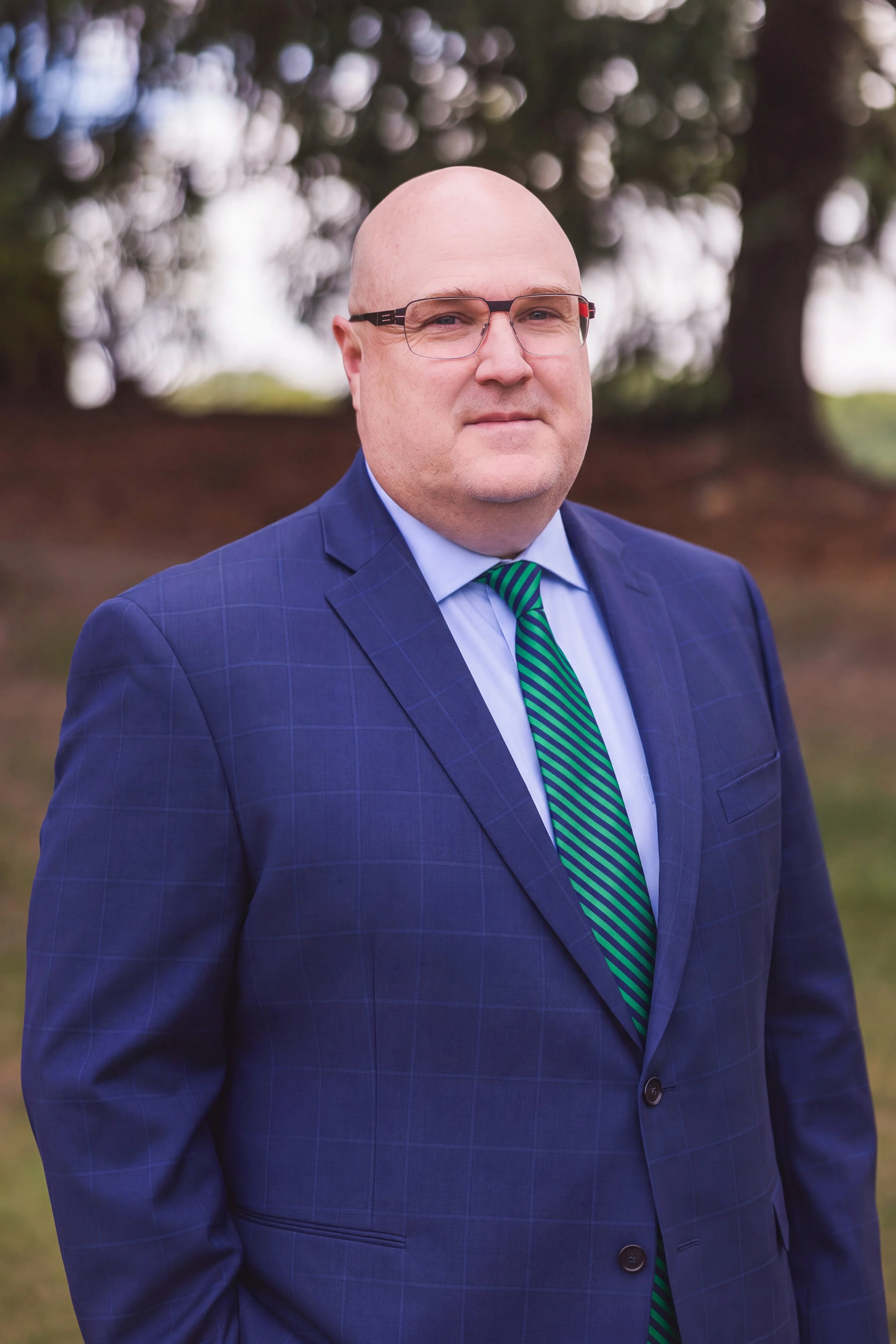 Man in suit with glasses, colorful tie, indoor setting