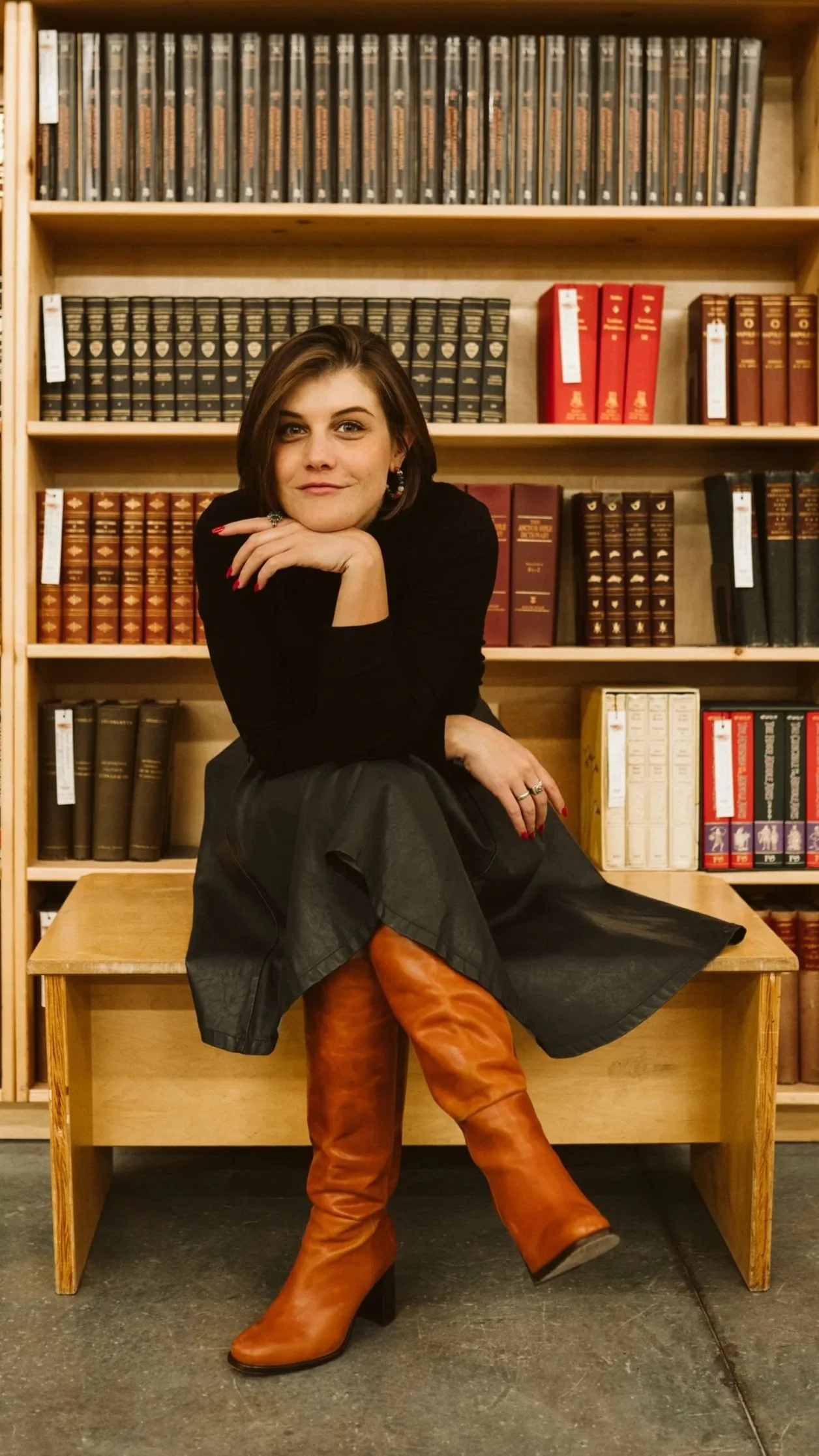 Meg Pompetti rests her chin on her hand, seated on a library bench