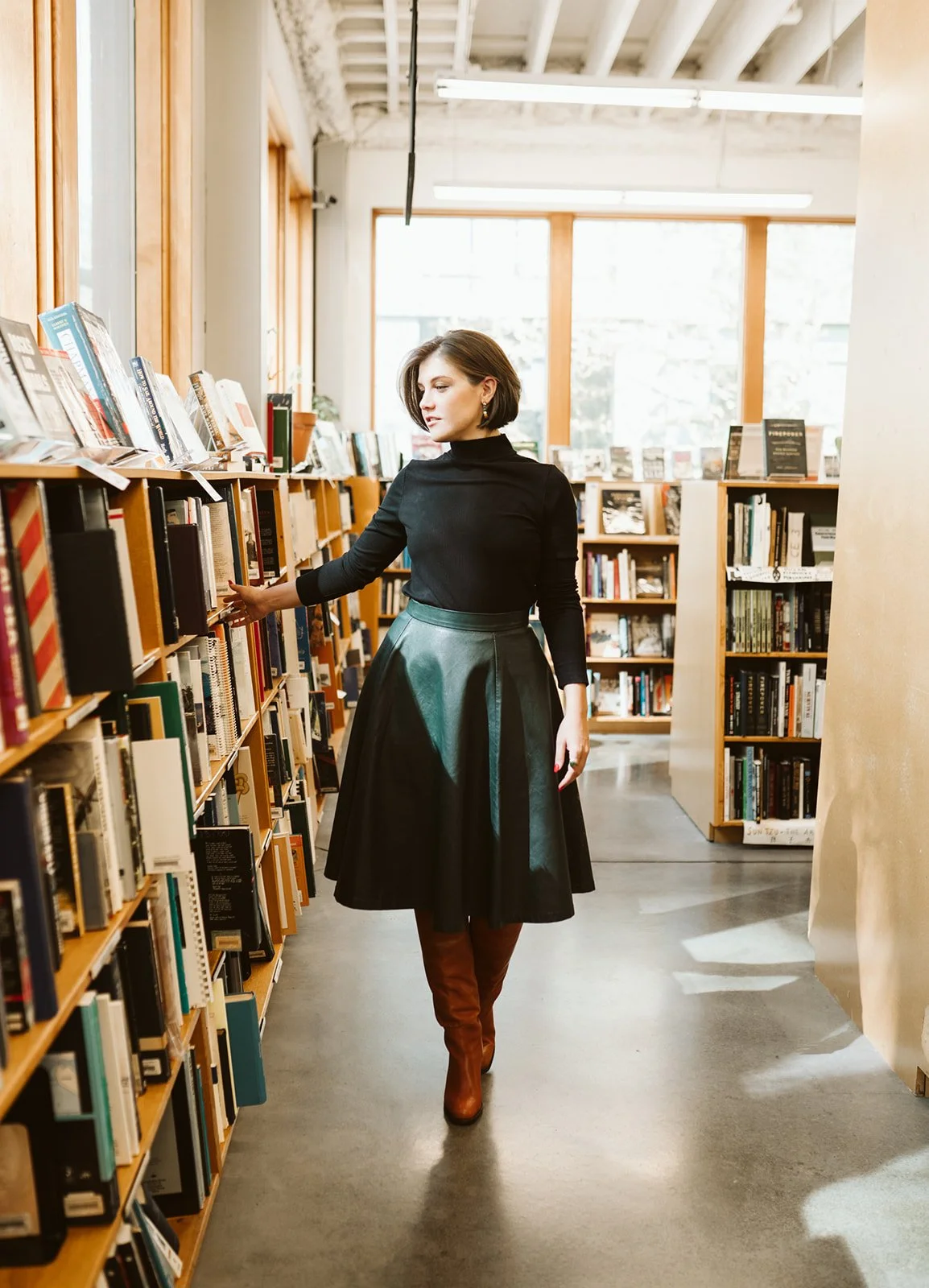 Meg walks among the books in a light-filled library.