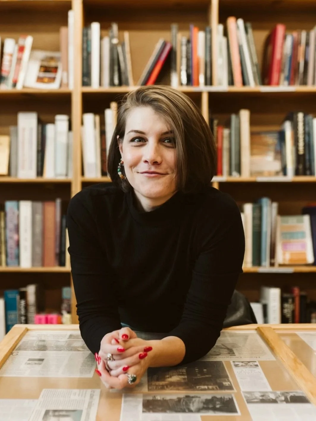 Meg Pompetti smiles against a backdrop of bookshelves.