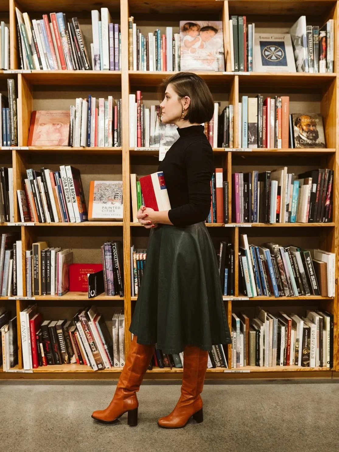 Meg in profile, standing beside a bookshelf.