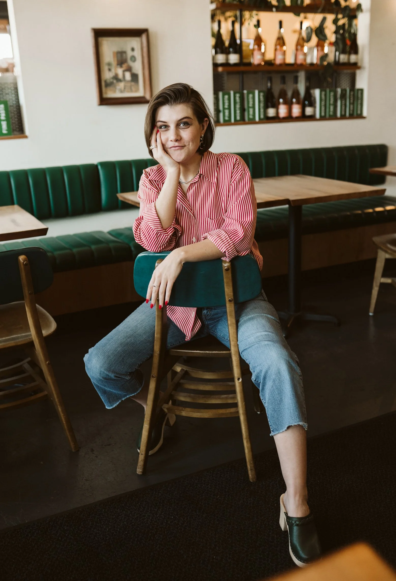 Meg Pompetti sits backwards in a chair, resting her chin in her hand.