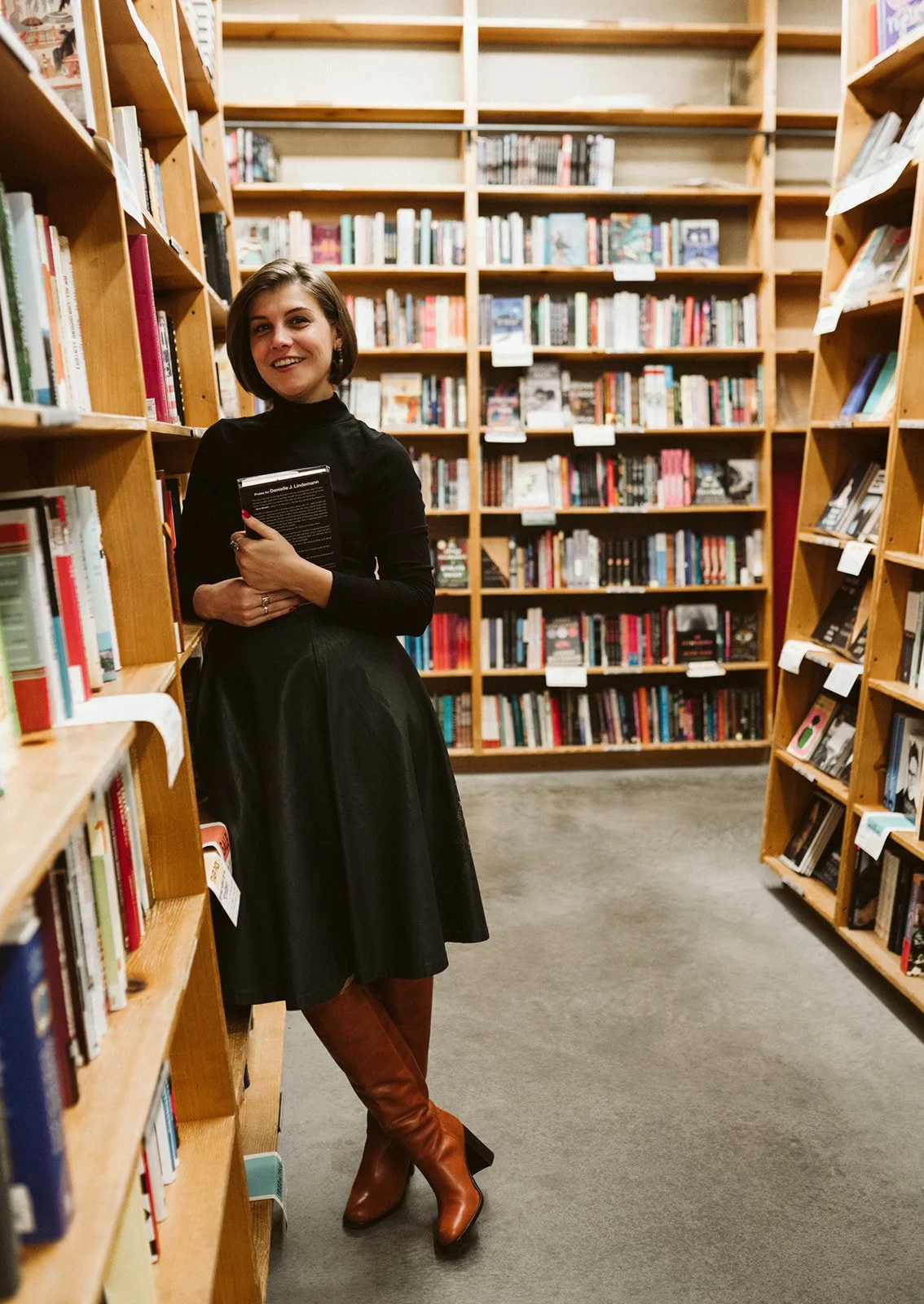 Meg leans against a bookshelf